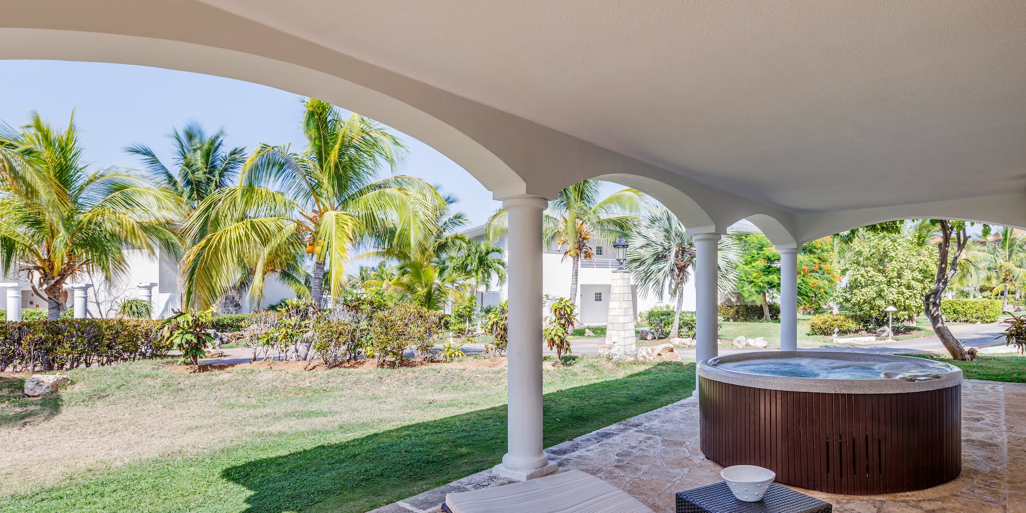 a hot tub with a table and chairs on a patio with palm trees