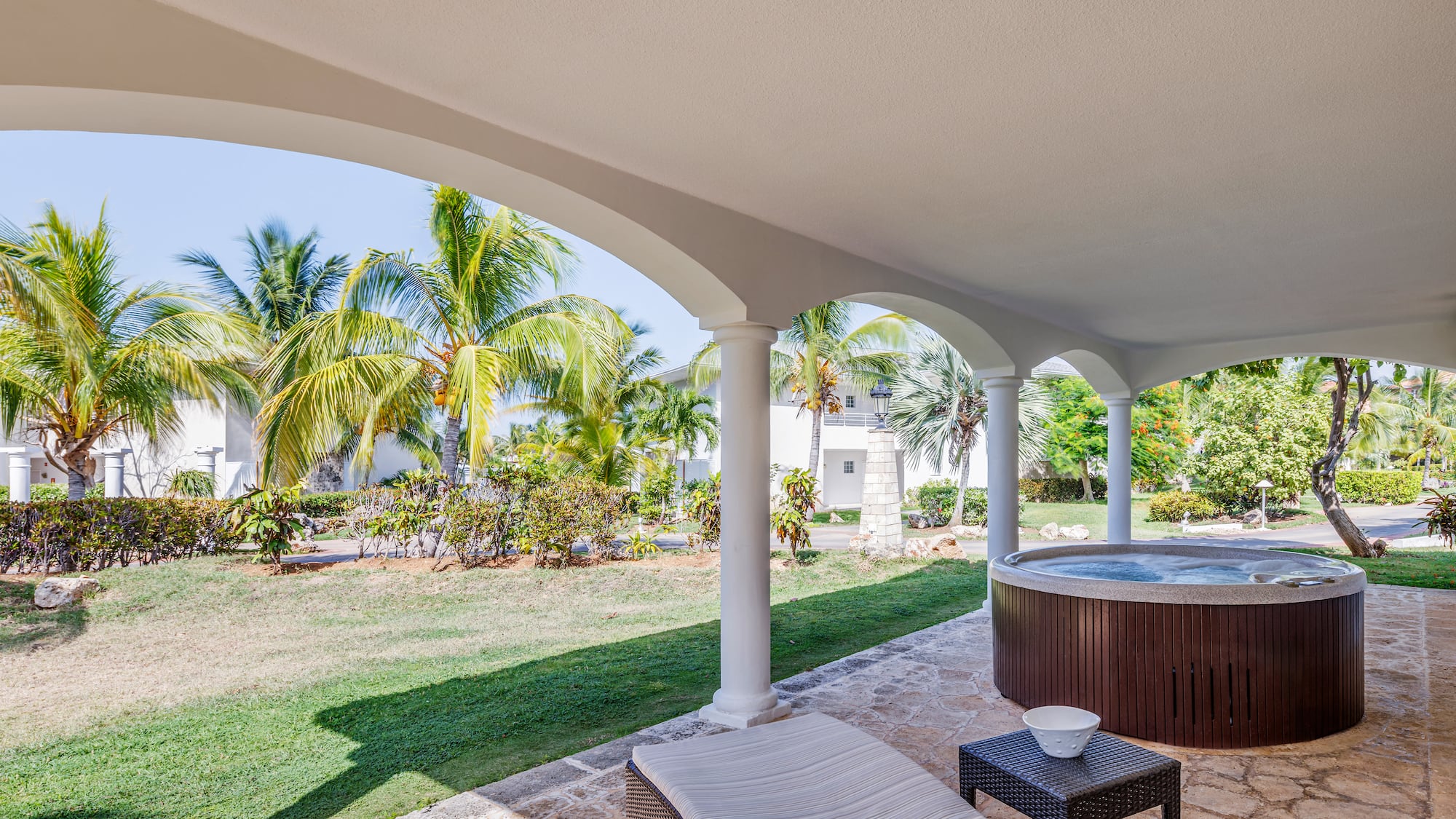 a hot tub with a table and chairs on a patio with palm trees