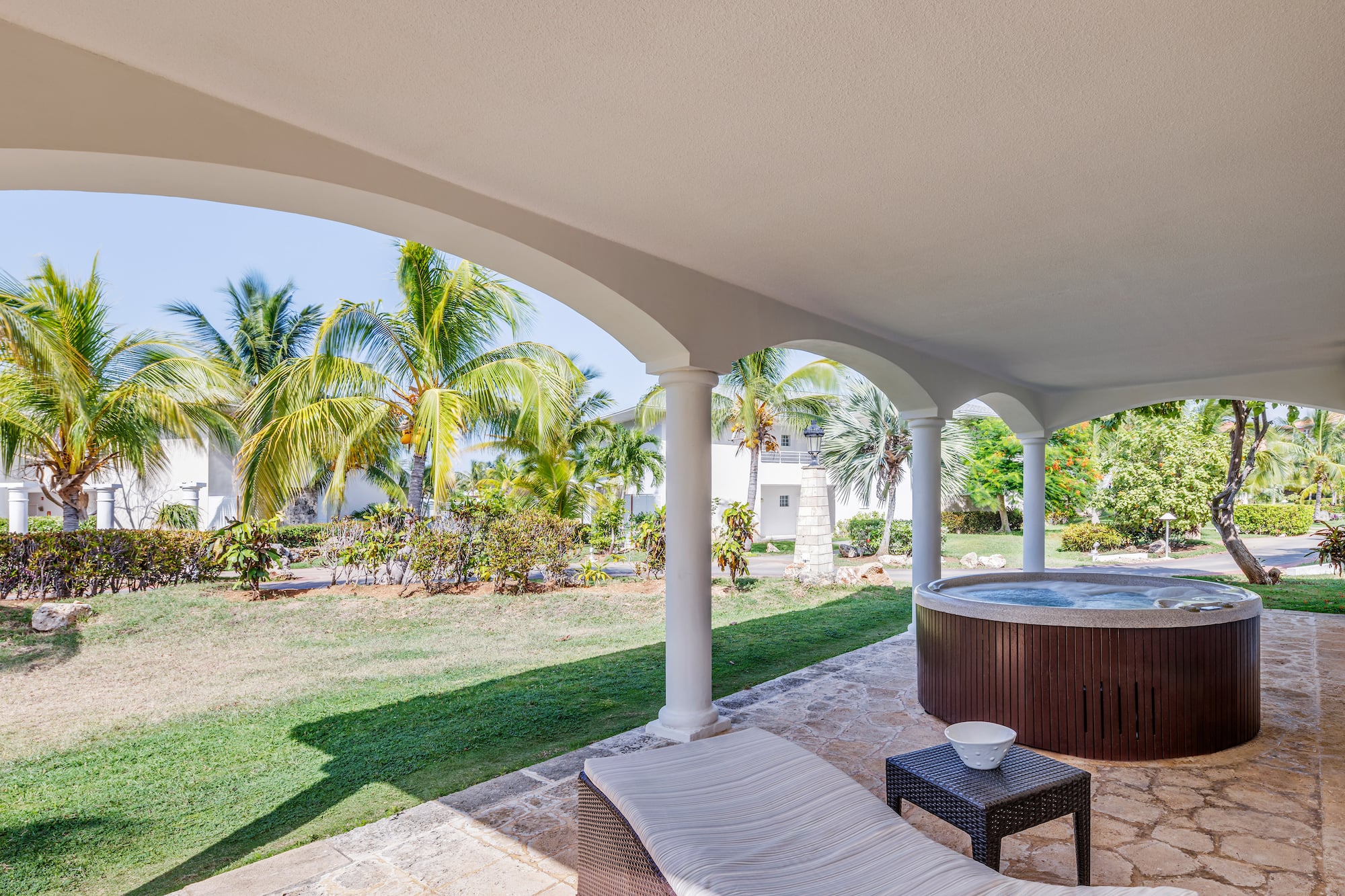 a hot tub with a table and chairs on a patio with palm trees