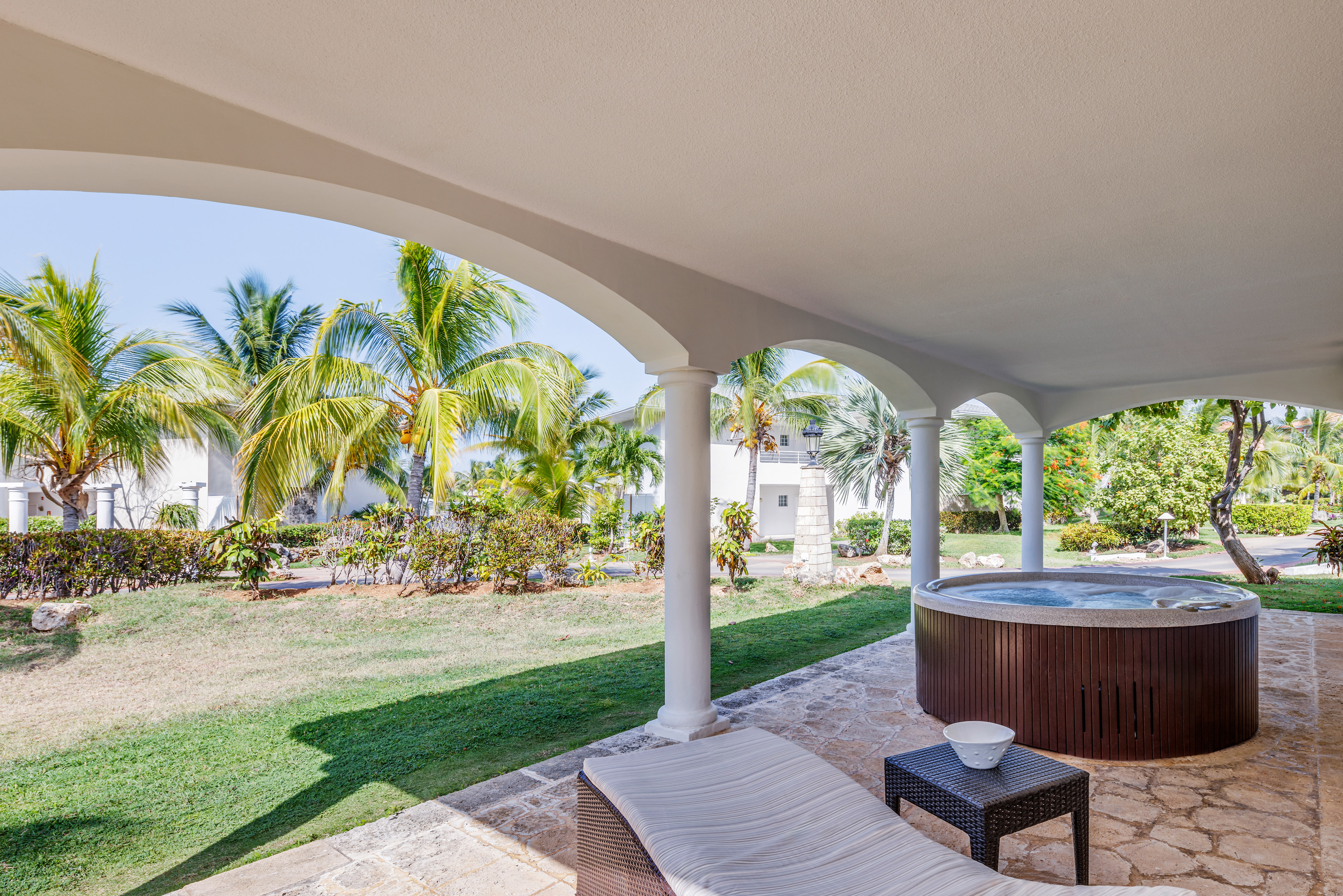 a hot tub with a table and chairs on a patio with palm trees