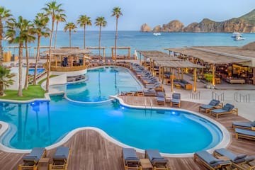 Cabo San Lucas luxury resort with pools, palm trees, ocean, and El Arco.