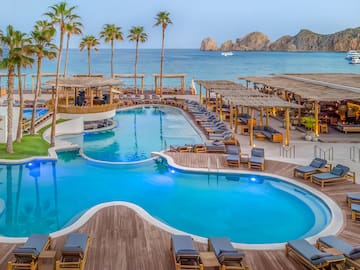 Cabo San Lucas luxury resort with pools, palm trees, ocean, and El Arco.