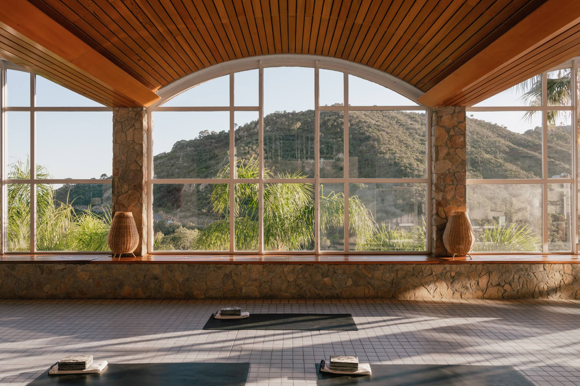 Serene wellness yoga studio with mountain view, arched windows, and wood ceiling.
