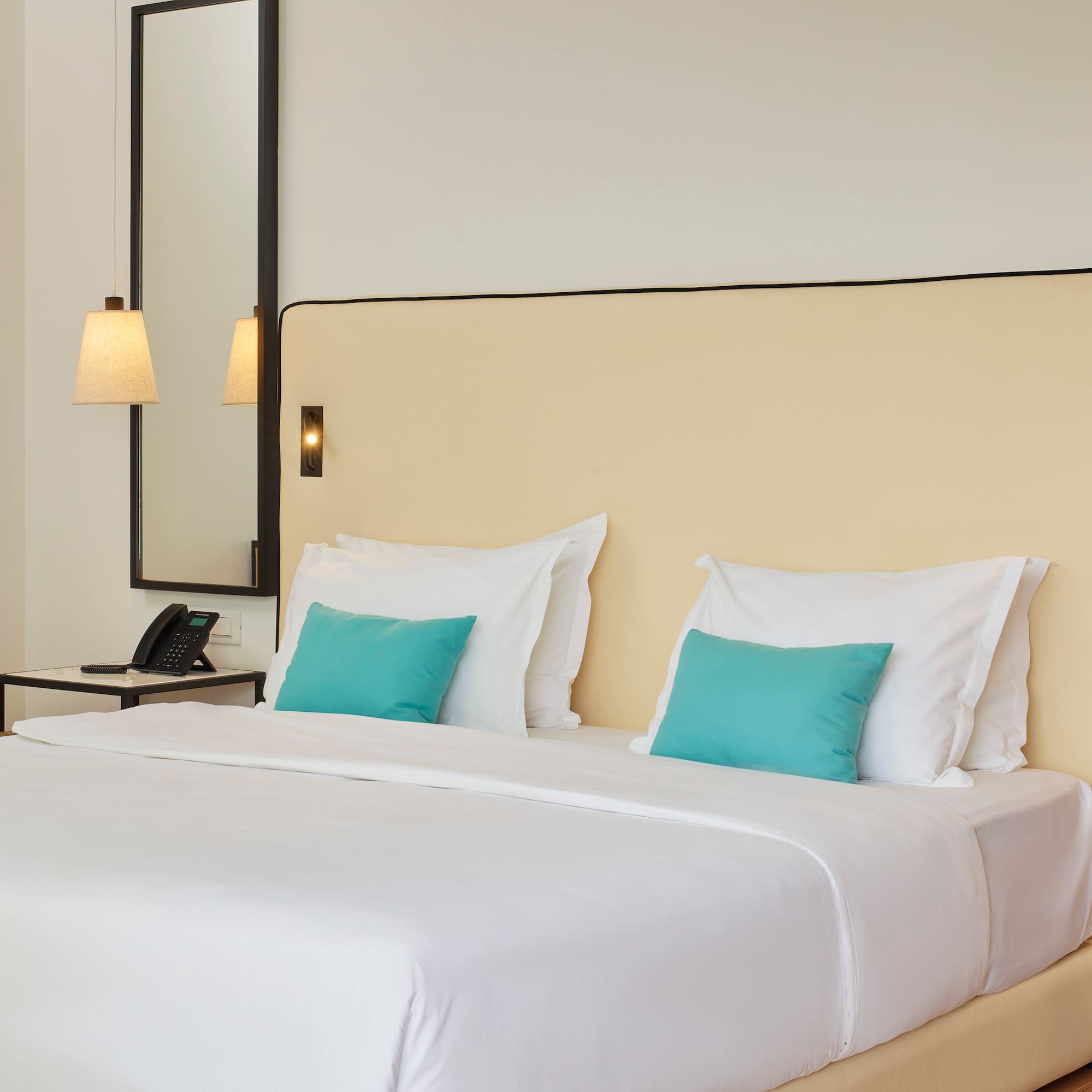 a bed with white sheets and blue pillows