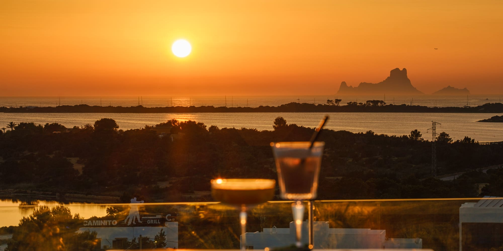 a table with drinks on it and a sunset in the background