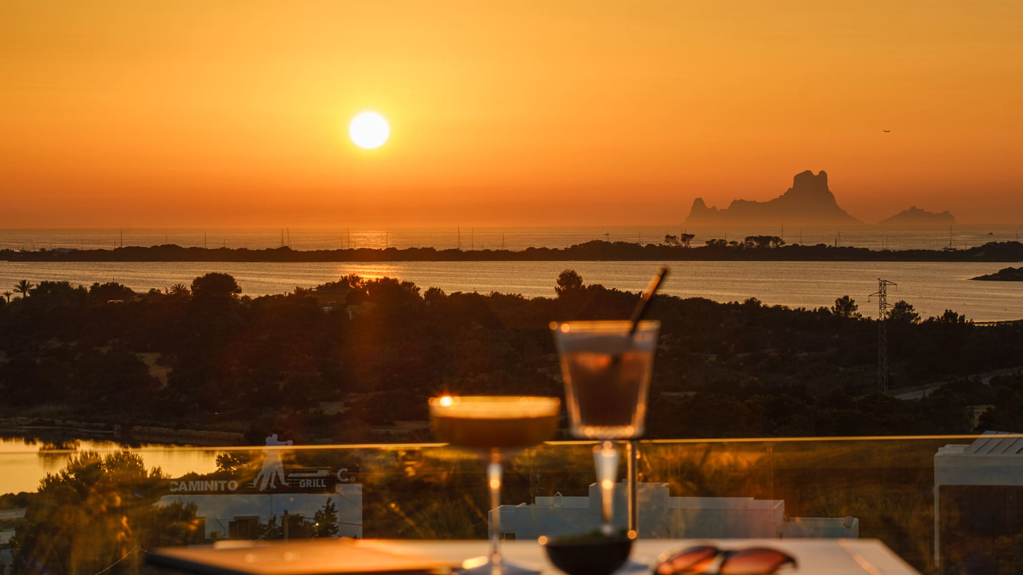 a table with drinks on it and a sunset in the background