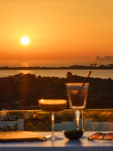 a table with drinks on it and a sunset in the background