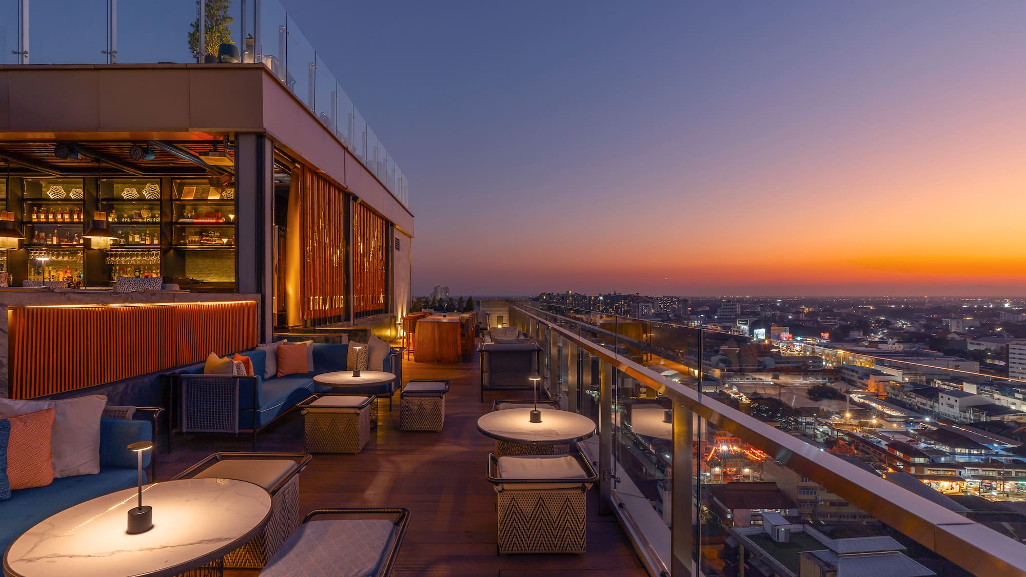a rooftop bar with tables and chairs and a city skyline