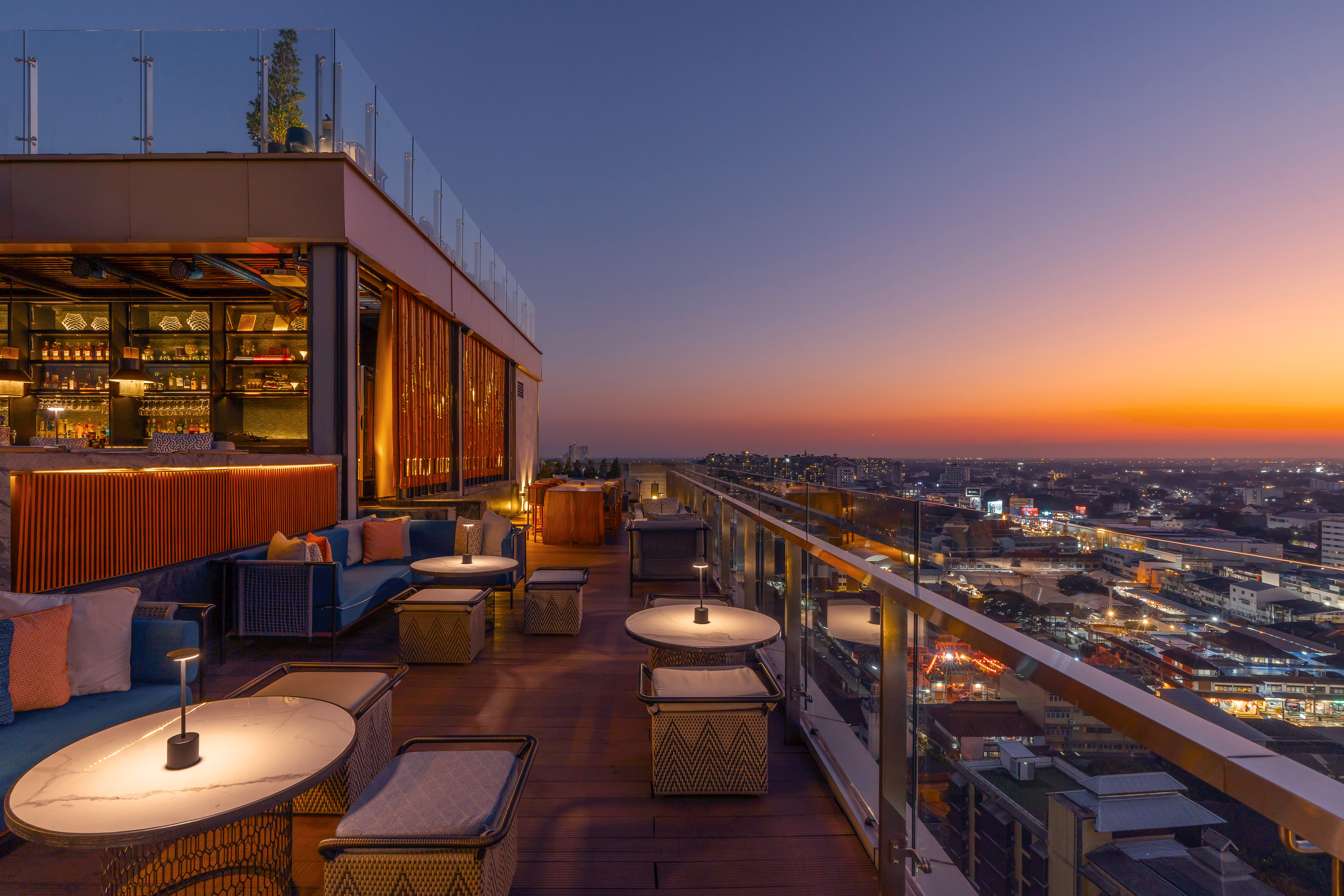 a rooftop bar with tables and chairs and a city skyline