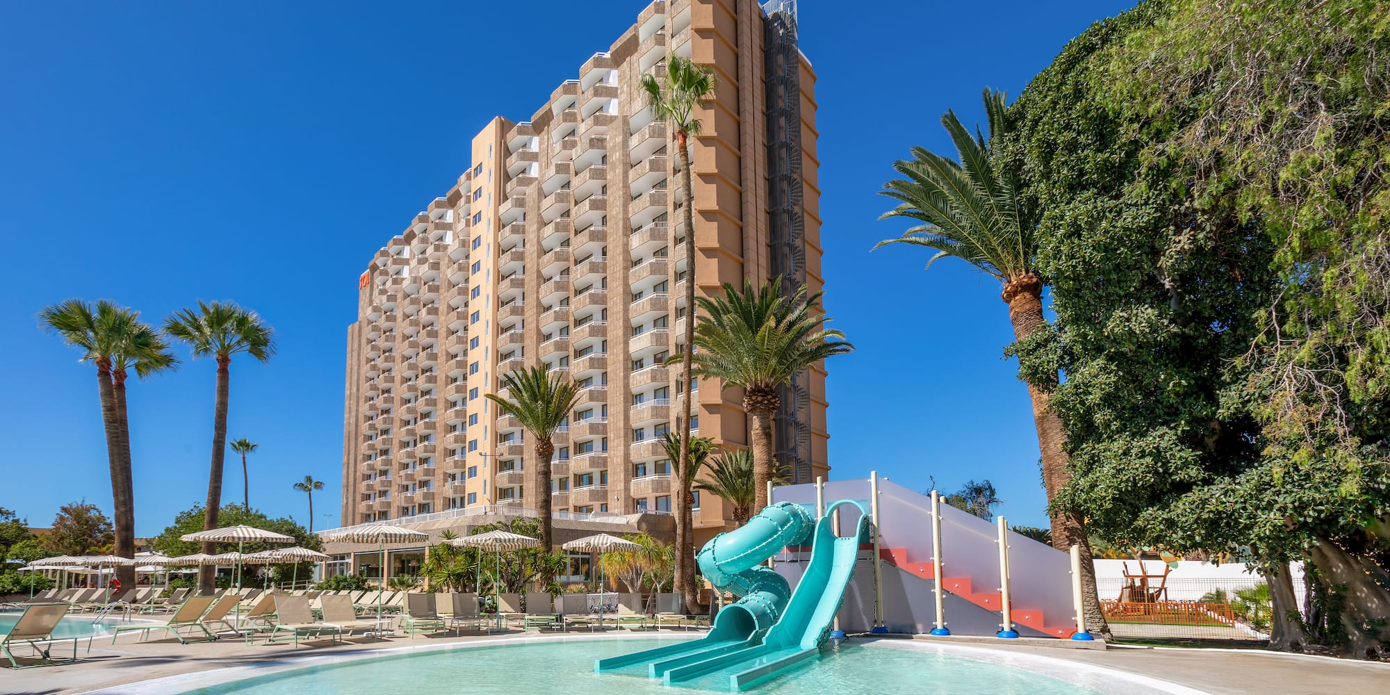 a pool with a slide in front of a building