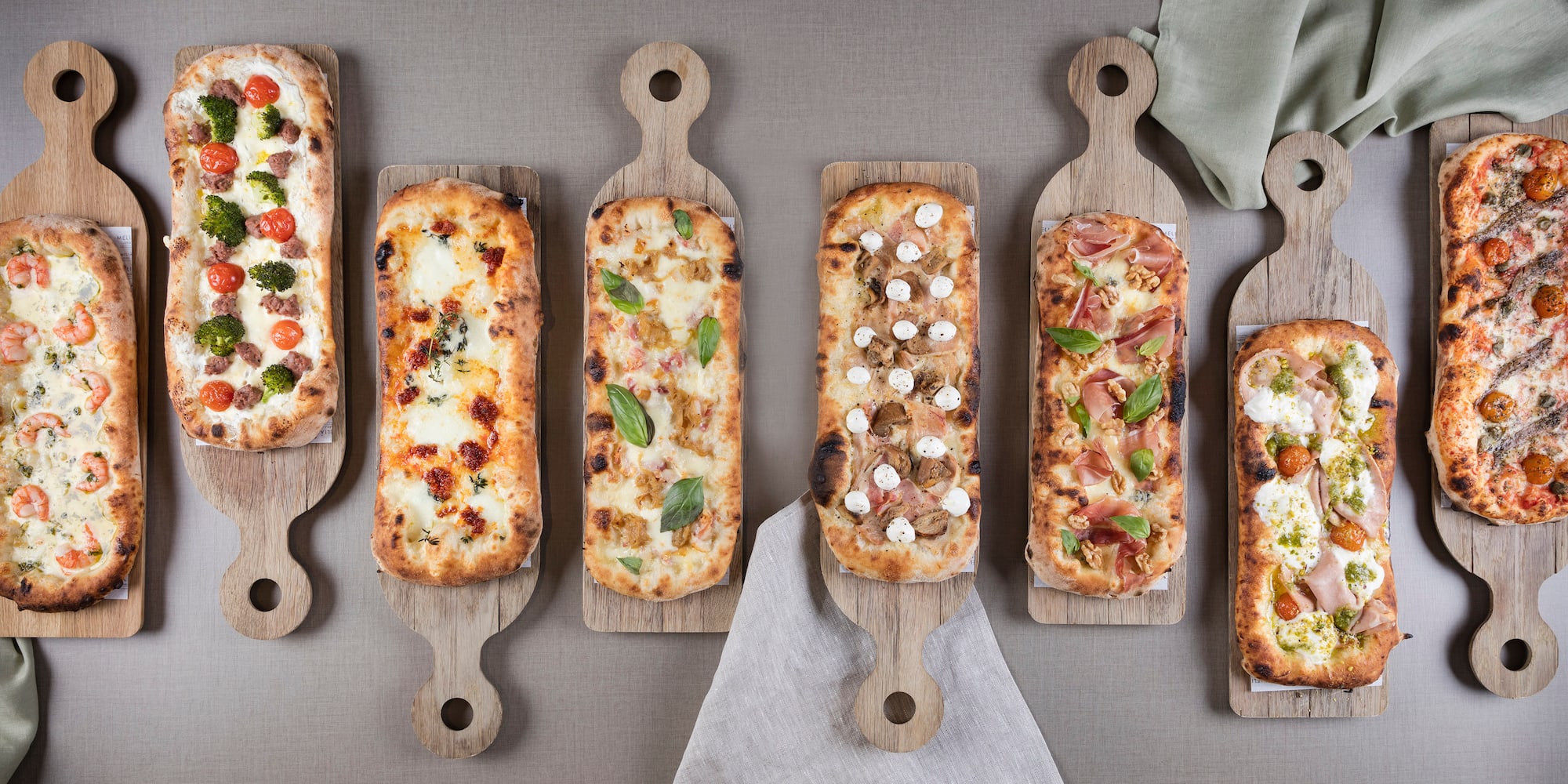 several rectangular pizzas on wooden boards