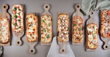 several rectangular pizzas on wooden boards