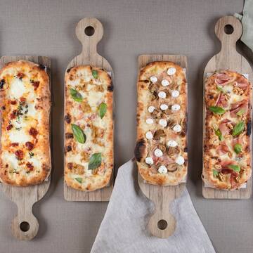several rectangular pizzas on wooden boards