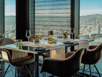 a table set for a dinner with chairs and glasses