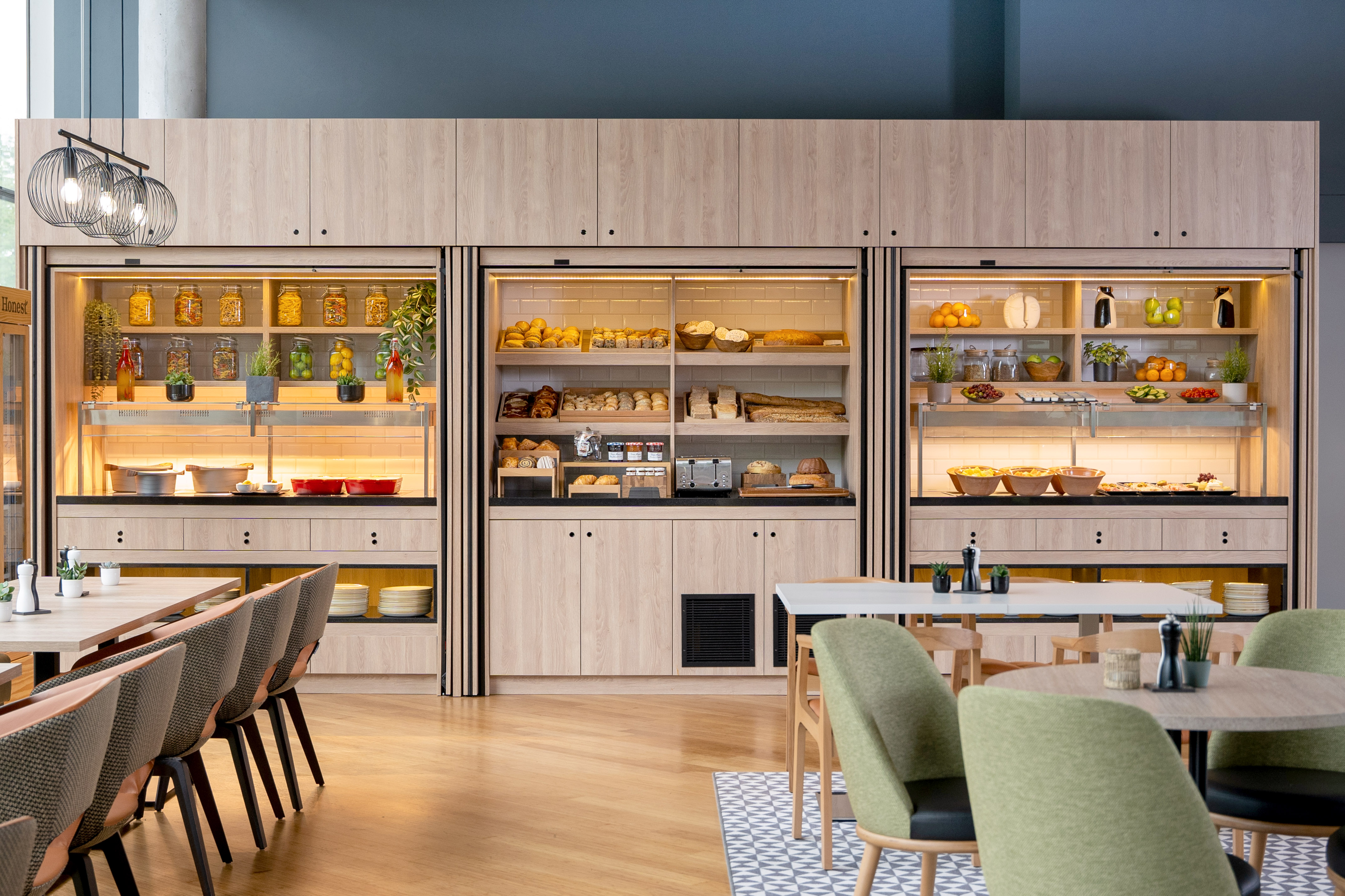 Hotel breakfast buffet with bakery, fresh fruit, hot food, and modern dining area.