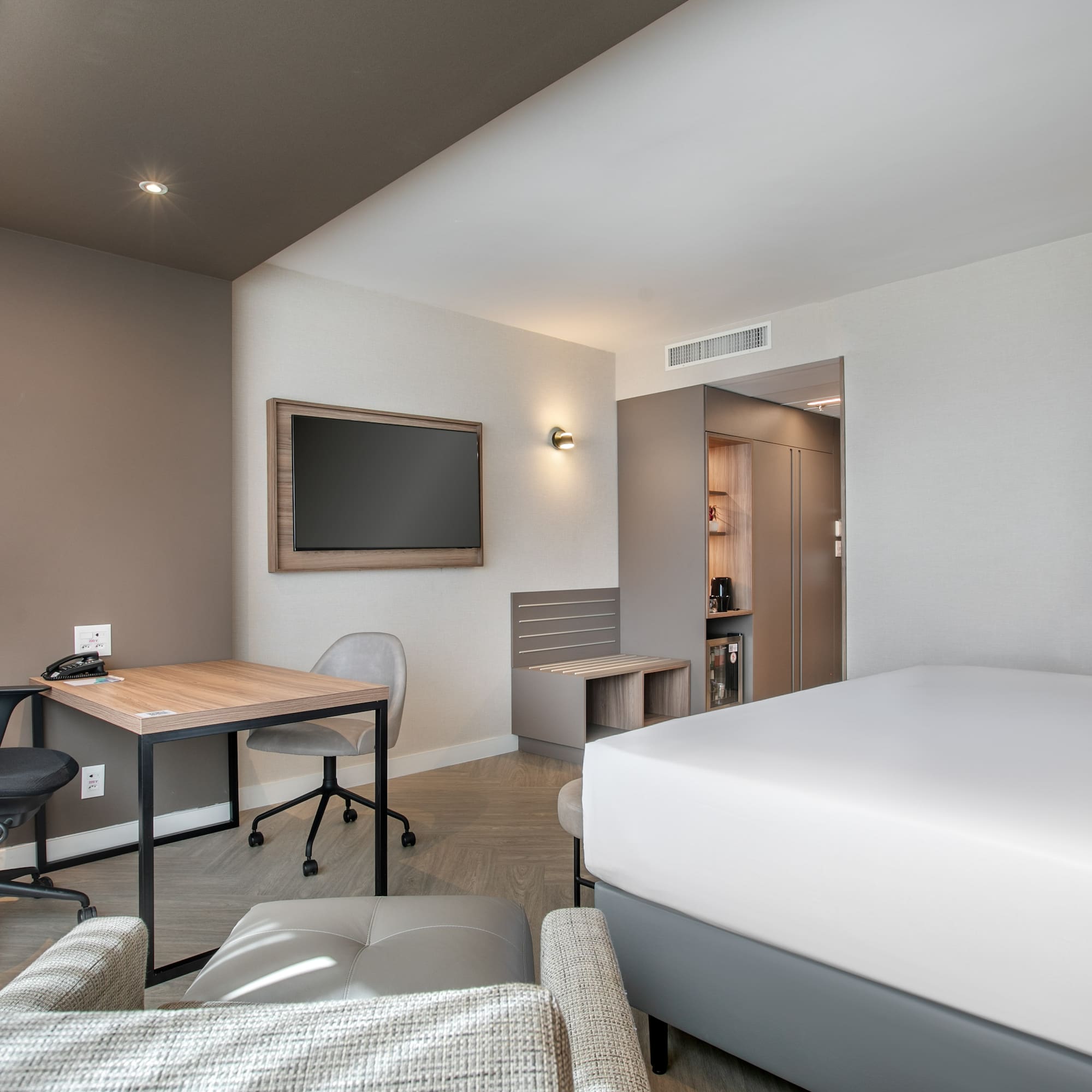 Sleek hotel room with bed, work desk, wall-mounted TV, and private bathroom.