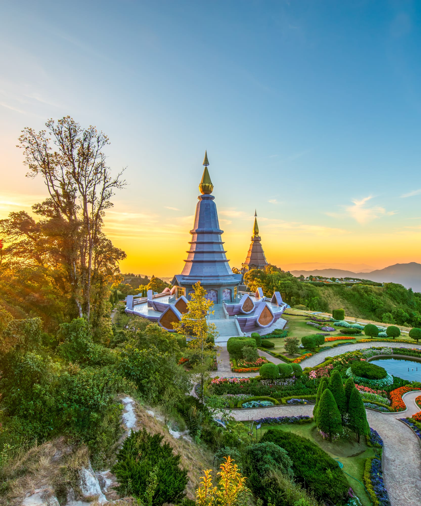 Golden pagodas, vibrant flower gardens, and mountains at sunrise, Doi Inthanon.