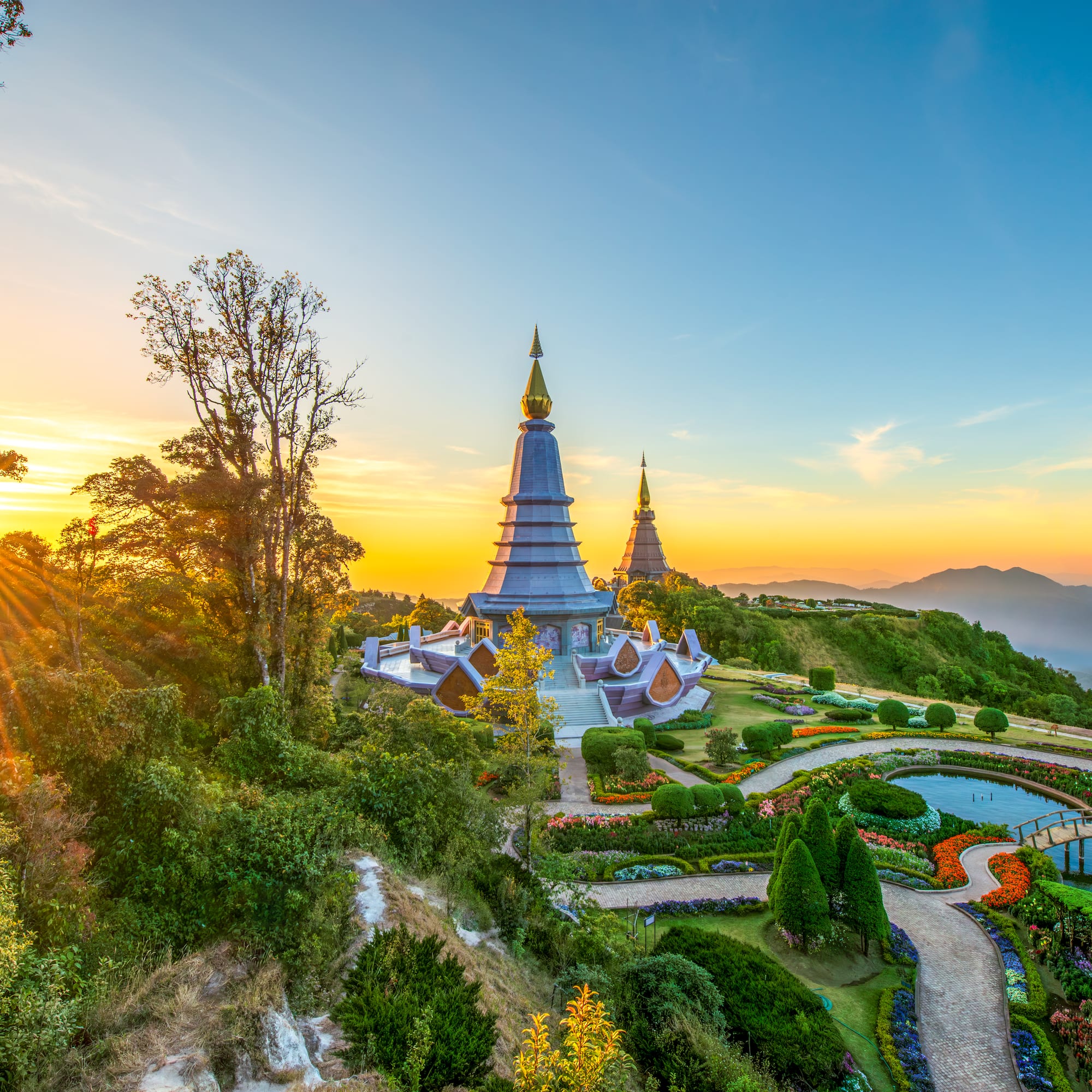 Golden pagodas, vibrant flower gardens, and mountains at sunrise, Doi Inthanon.