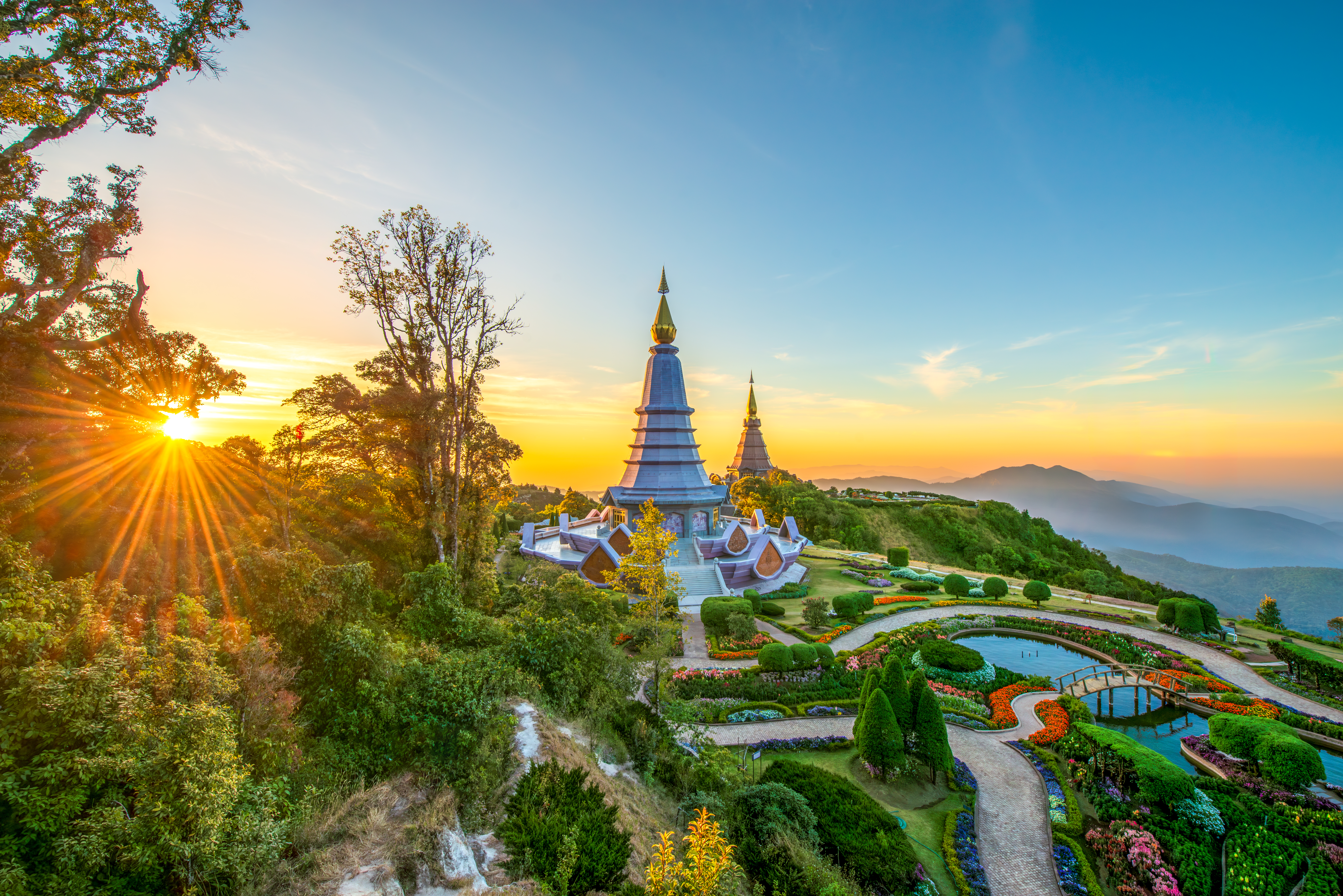 Golden pagodas, vibrant flower gardens, and mountains at sunrise, Doi Inthanon.