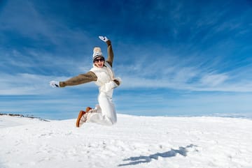 a woman jumping in the air in the snow