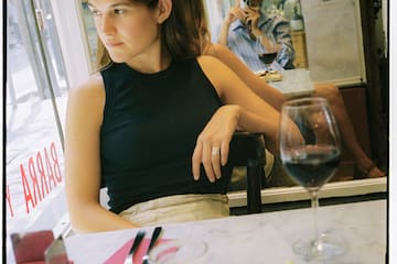 a woman sitting at a table with a man taking a picture of her