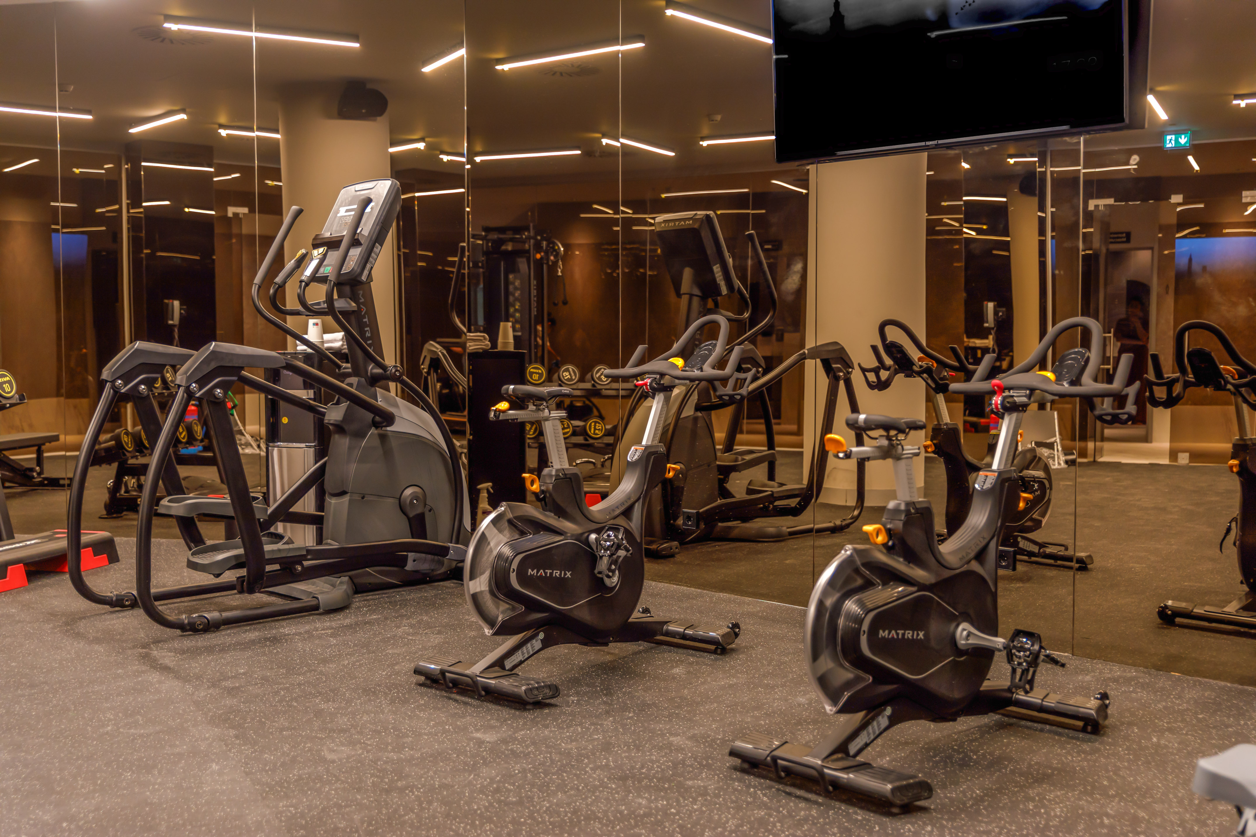 Modern fitness center with Matrix elliptical and spin bikes, mirrored walls.