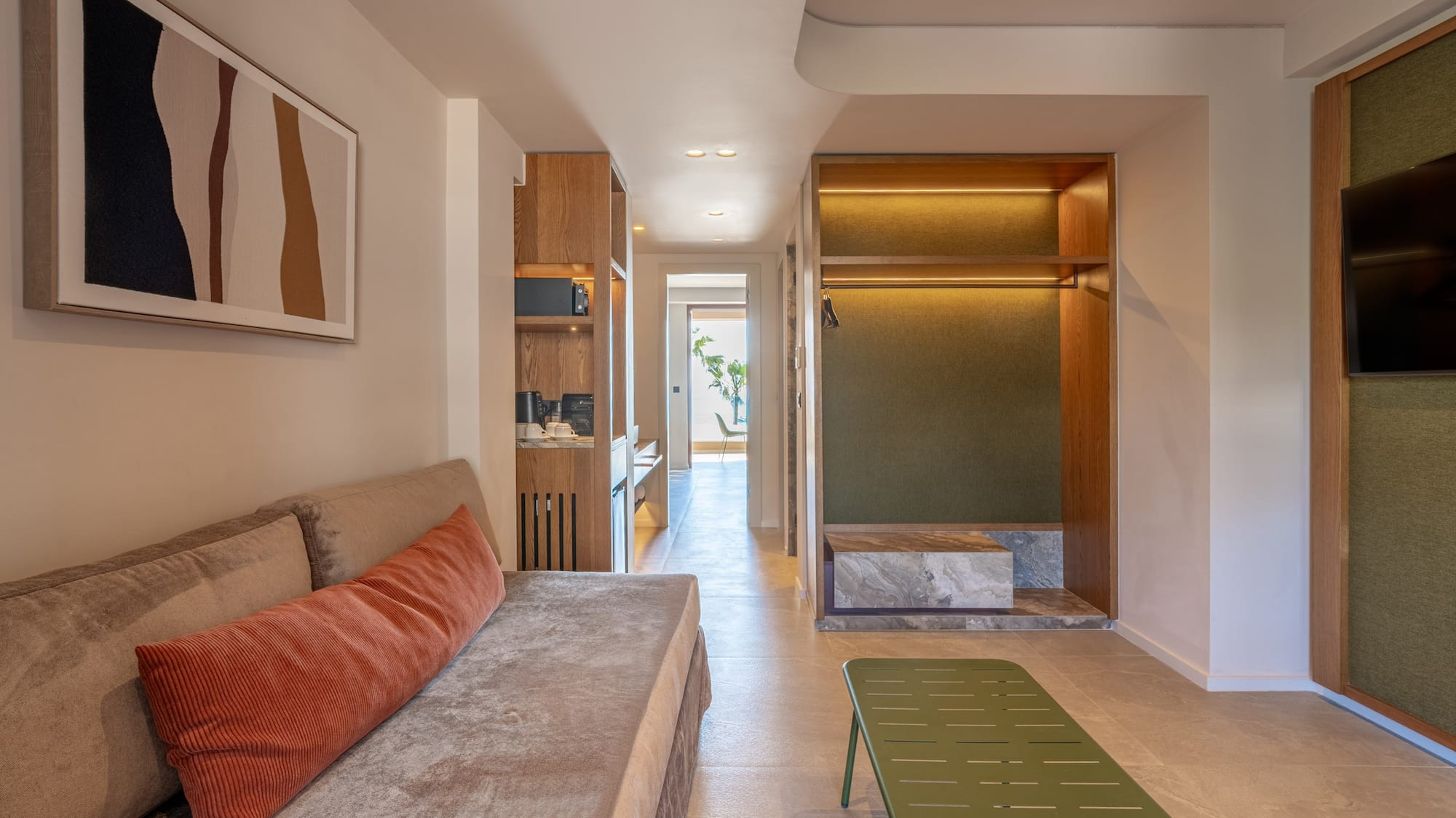 Contemporary hotel suite featuring living area, kitchenette, and open wardrobe.