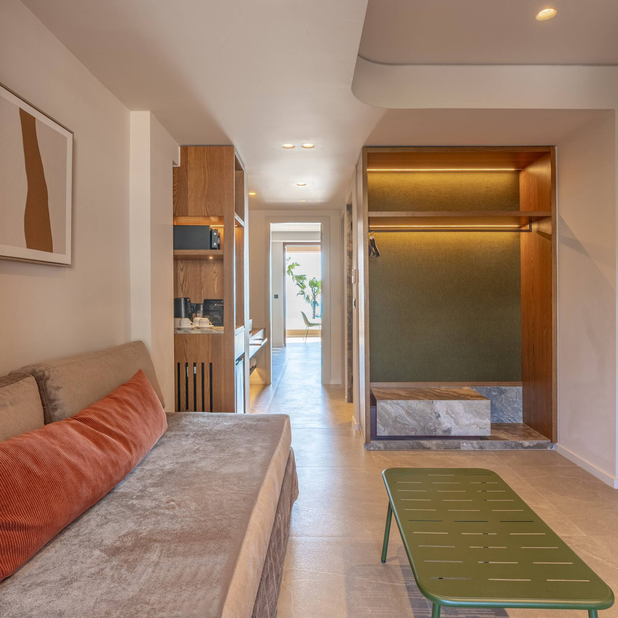 Contemporary hotel suite featuring living area, kitchenette, and open wardrobe.