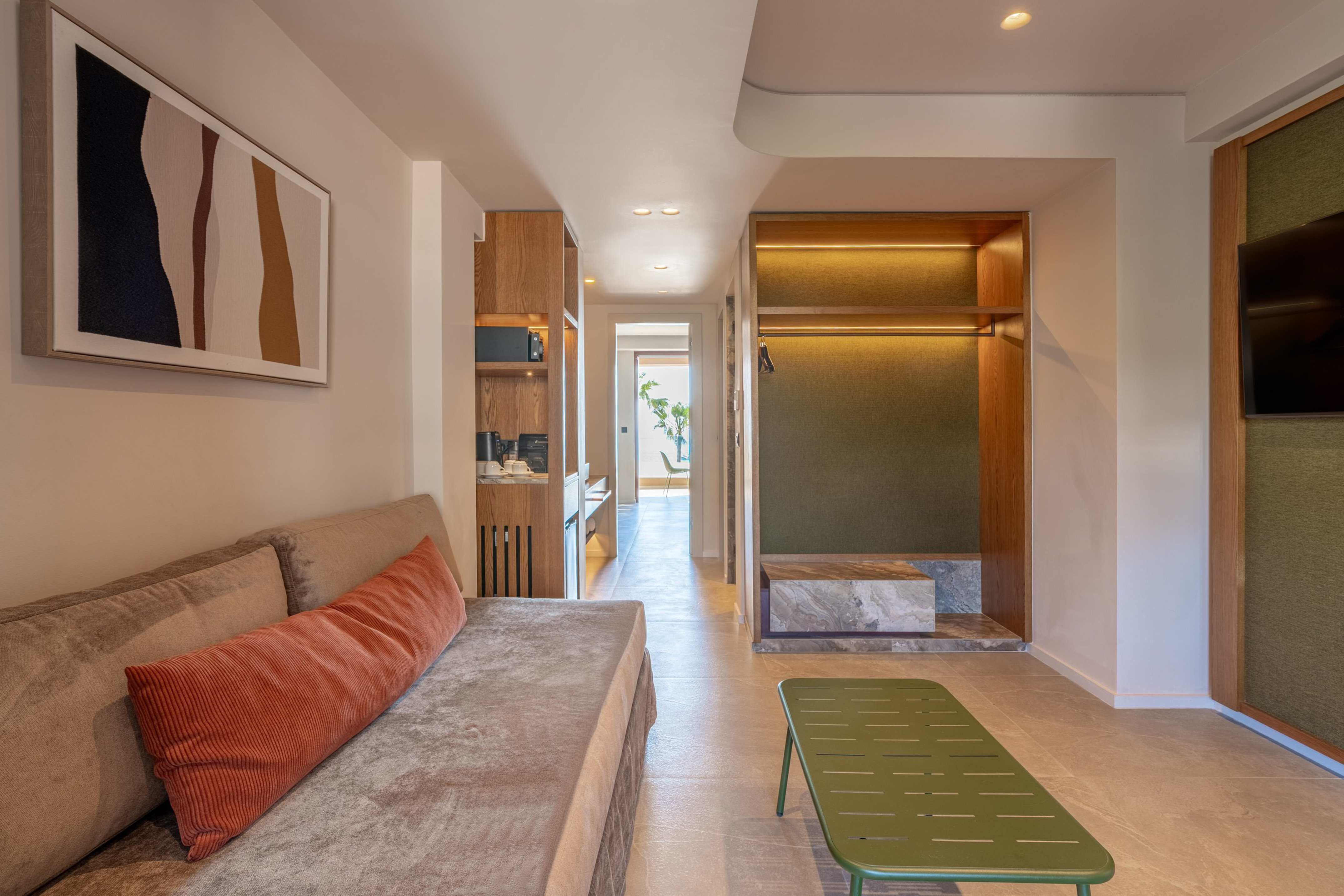 Contemporary hotel suite featuring living area, kitchenette, and open wardrobe.