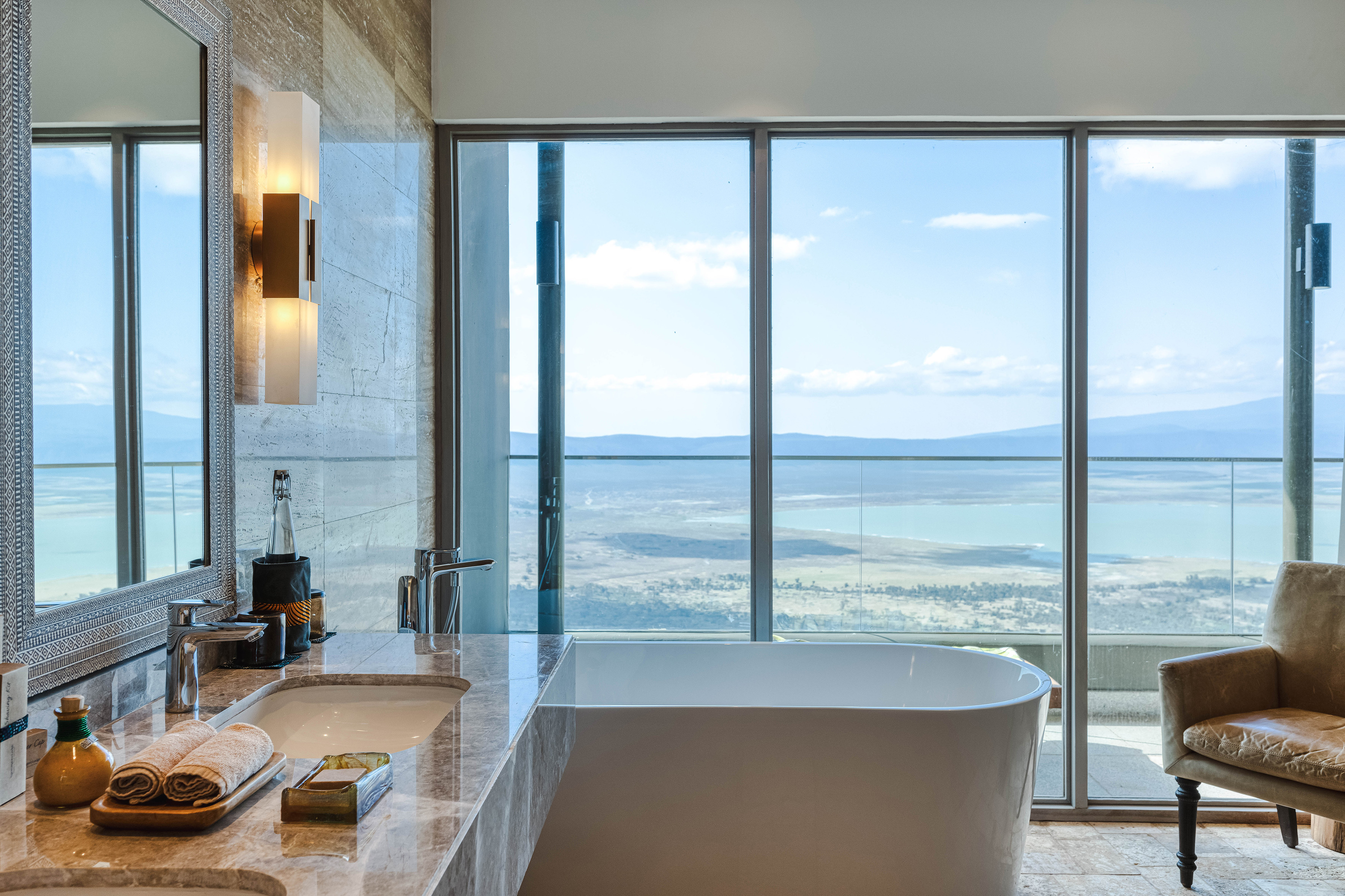 Modern bathroom with freestanding tub and scenic lake and mountain views.