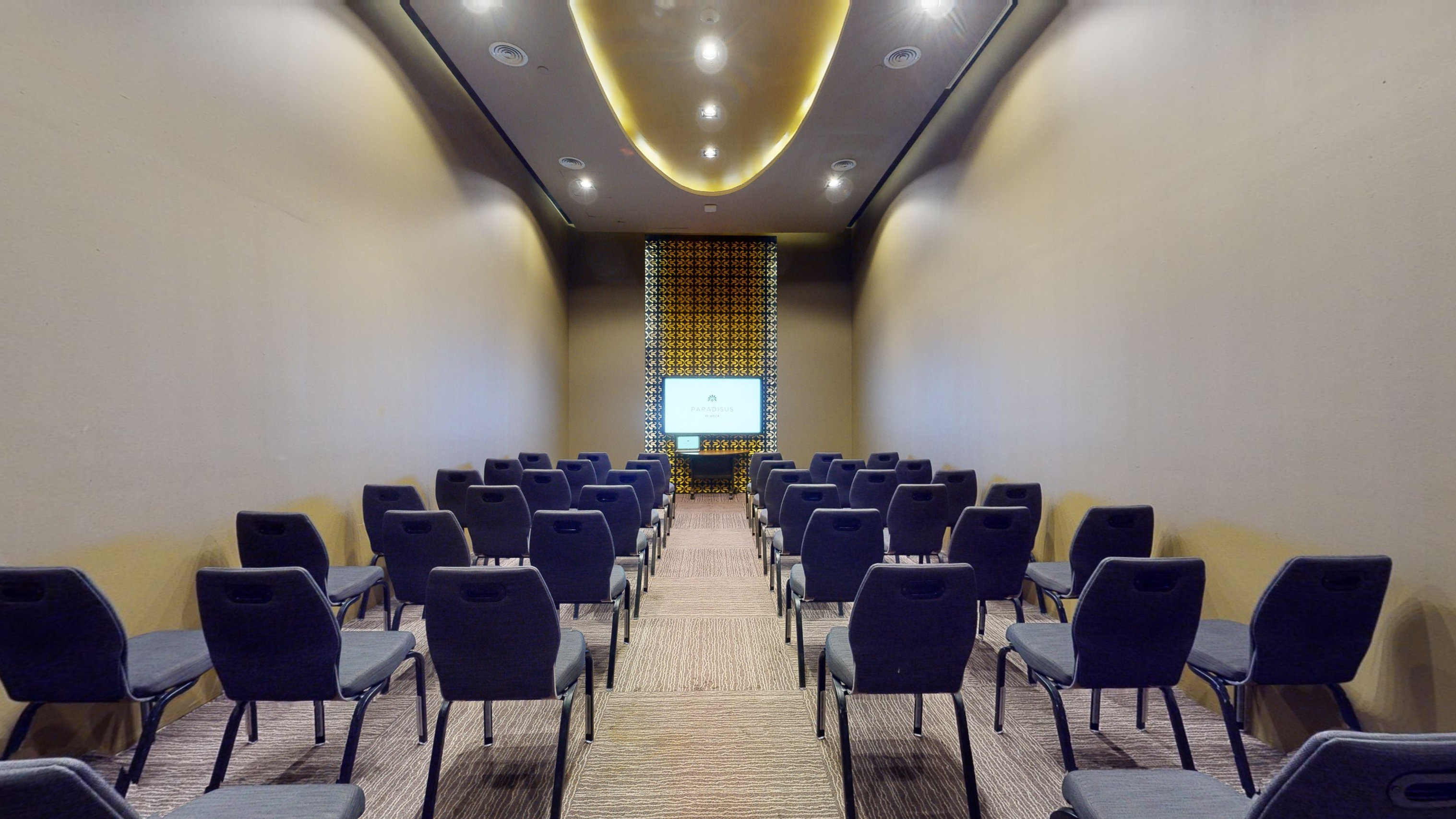 Hotel meeting room with dark chairs, presentation screen, and decorative wall panel.