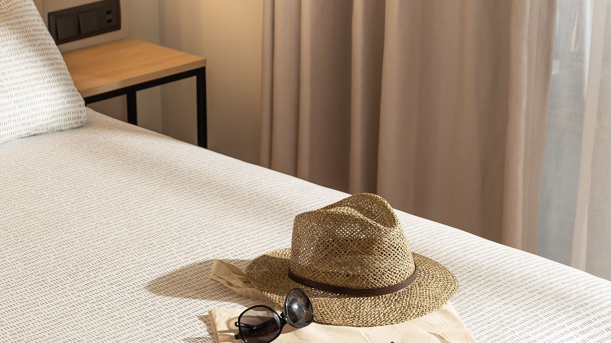 a hat and sunglasses on a bed