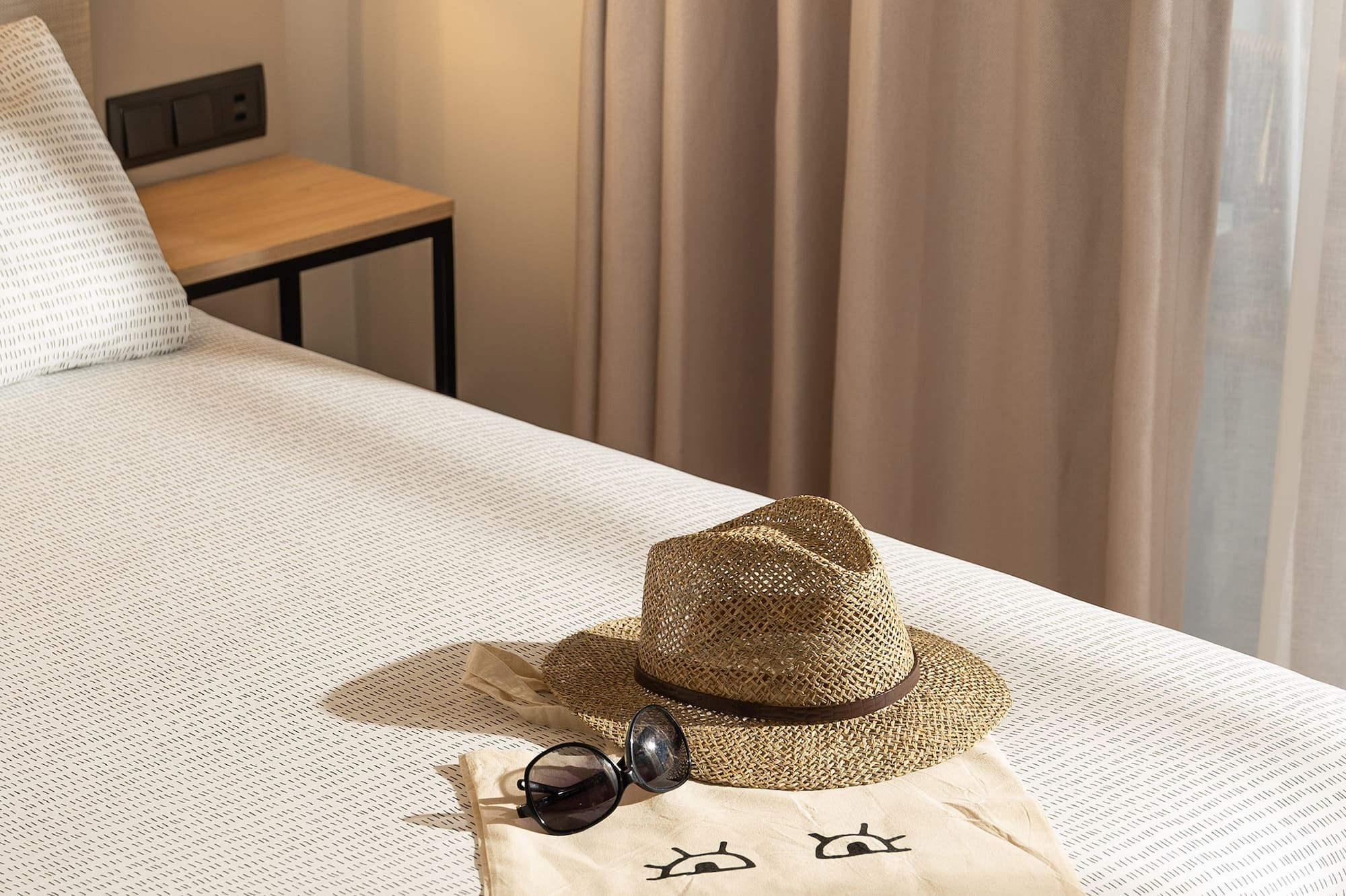 a hat and sunglasses on a bed