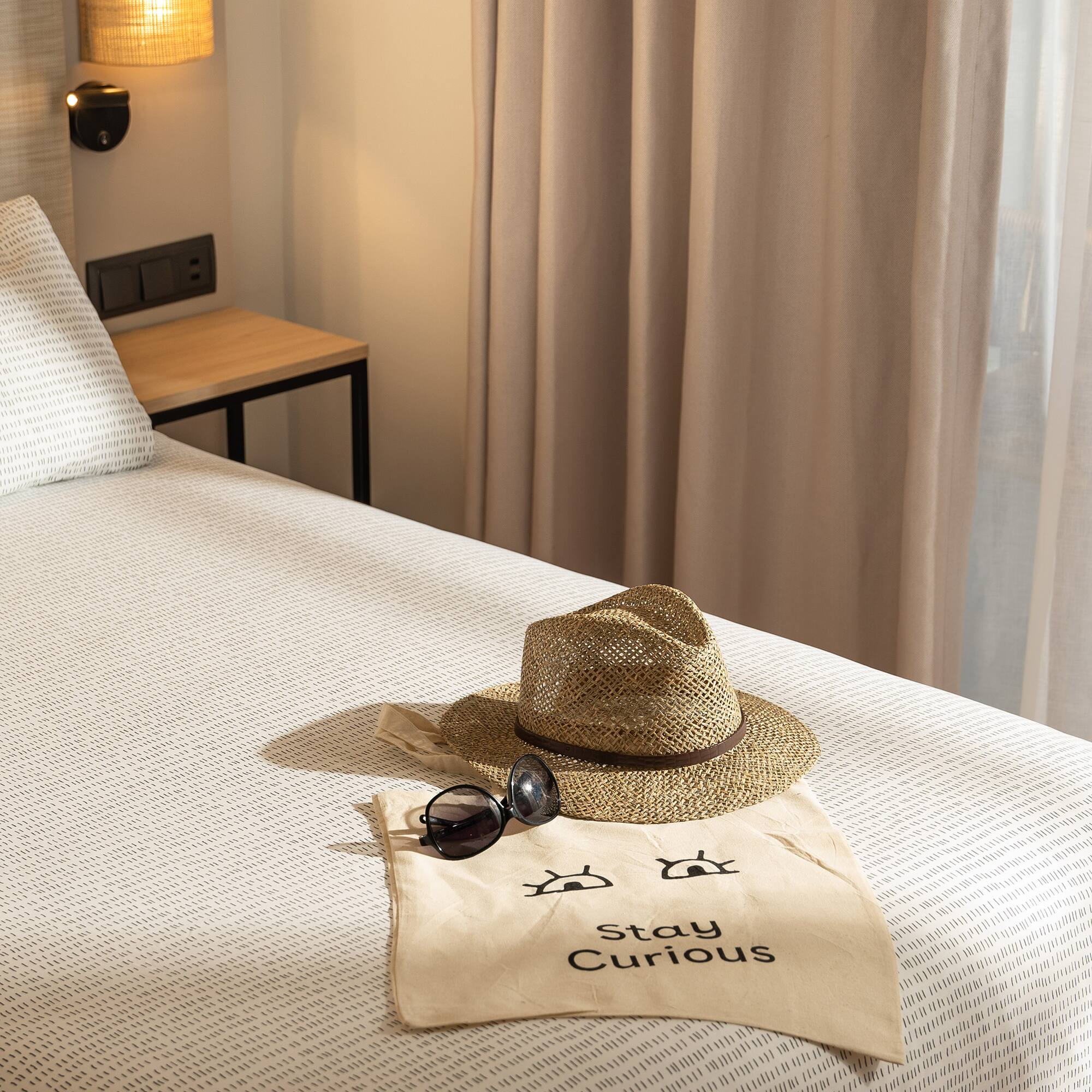 a hat and sunglasses on a bed