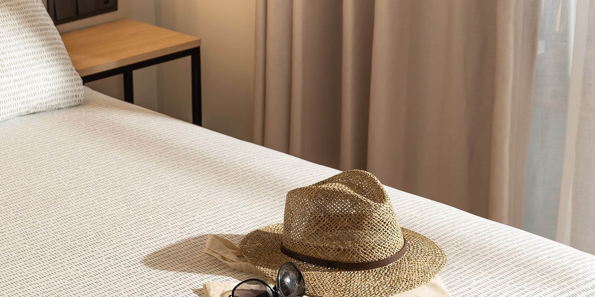 a hat and sunglasses on a bed