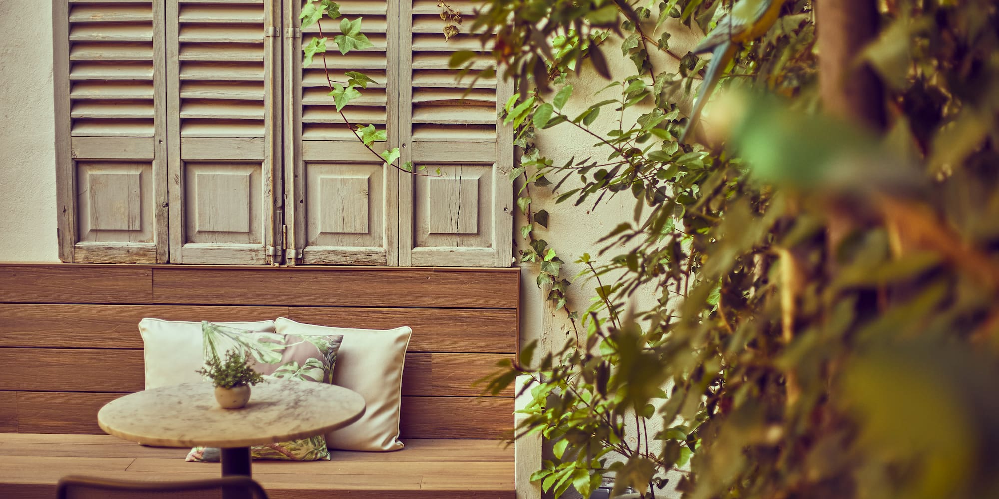 a table and chair outside with shutters