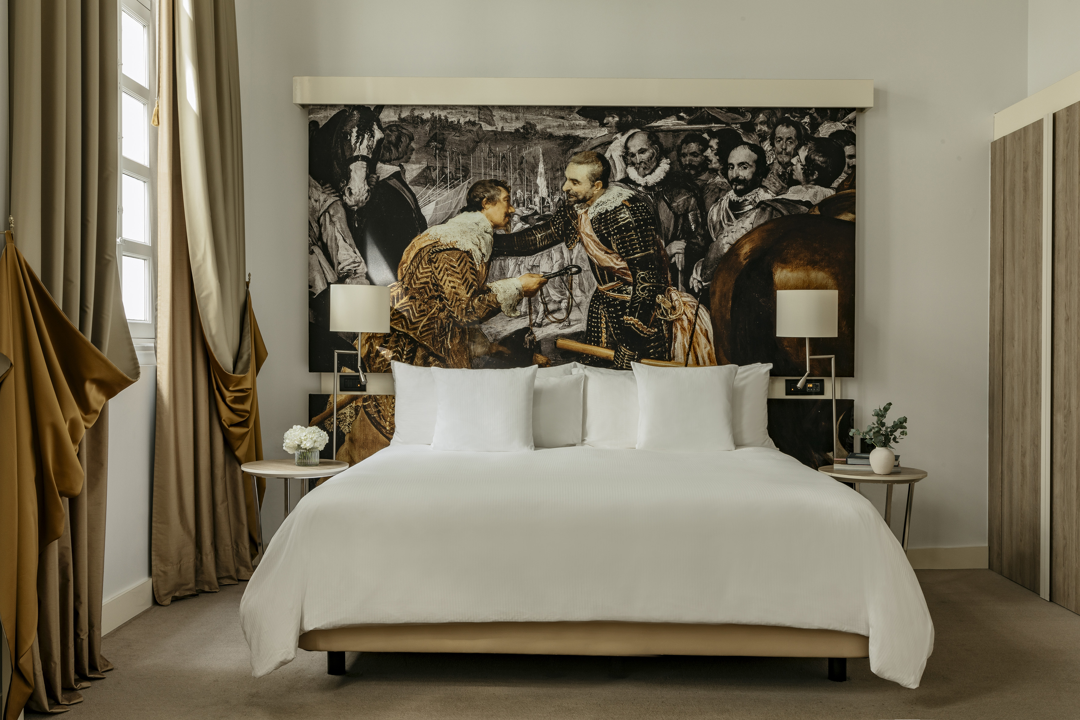 Hotel bedroom with historical art mural headboard and white king bed.