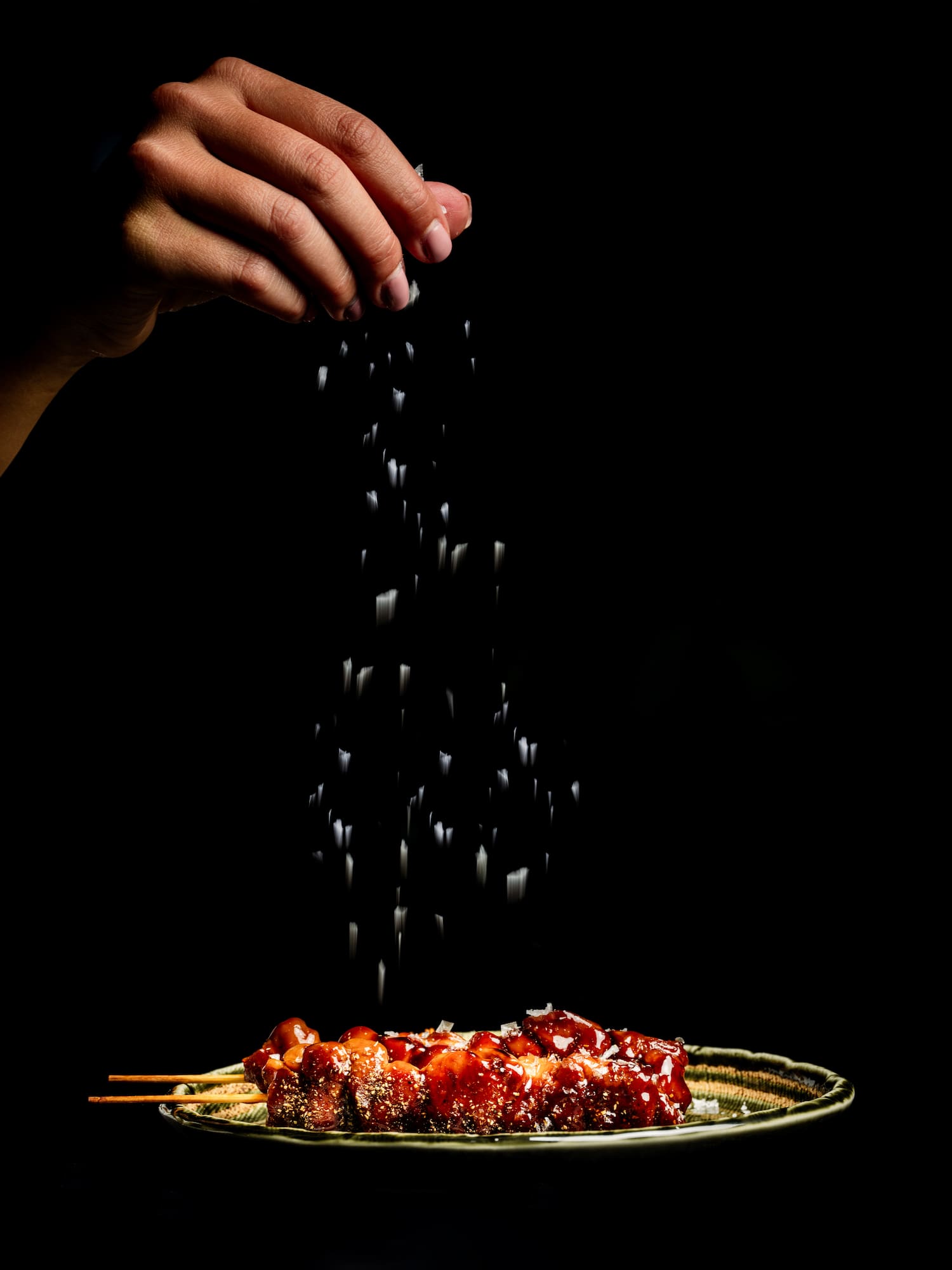 a hand sprinkling salt on food