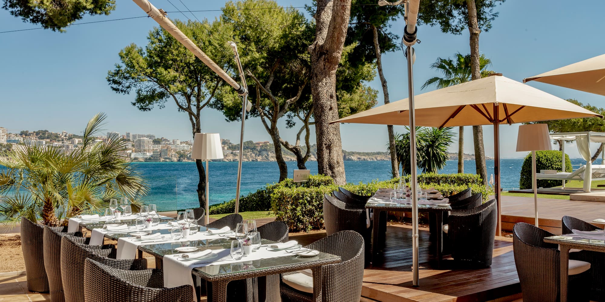 a table and chairs on a patio with a body of water in the background