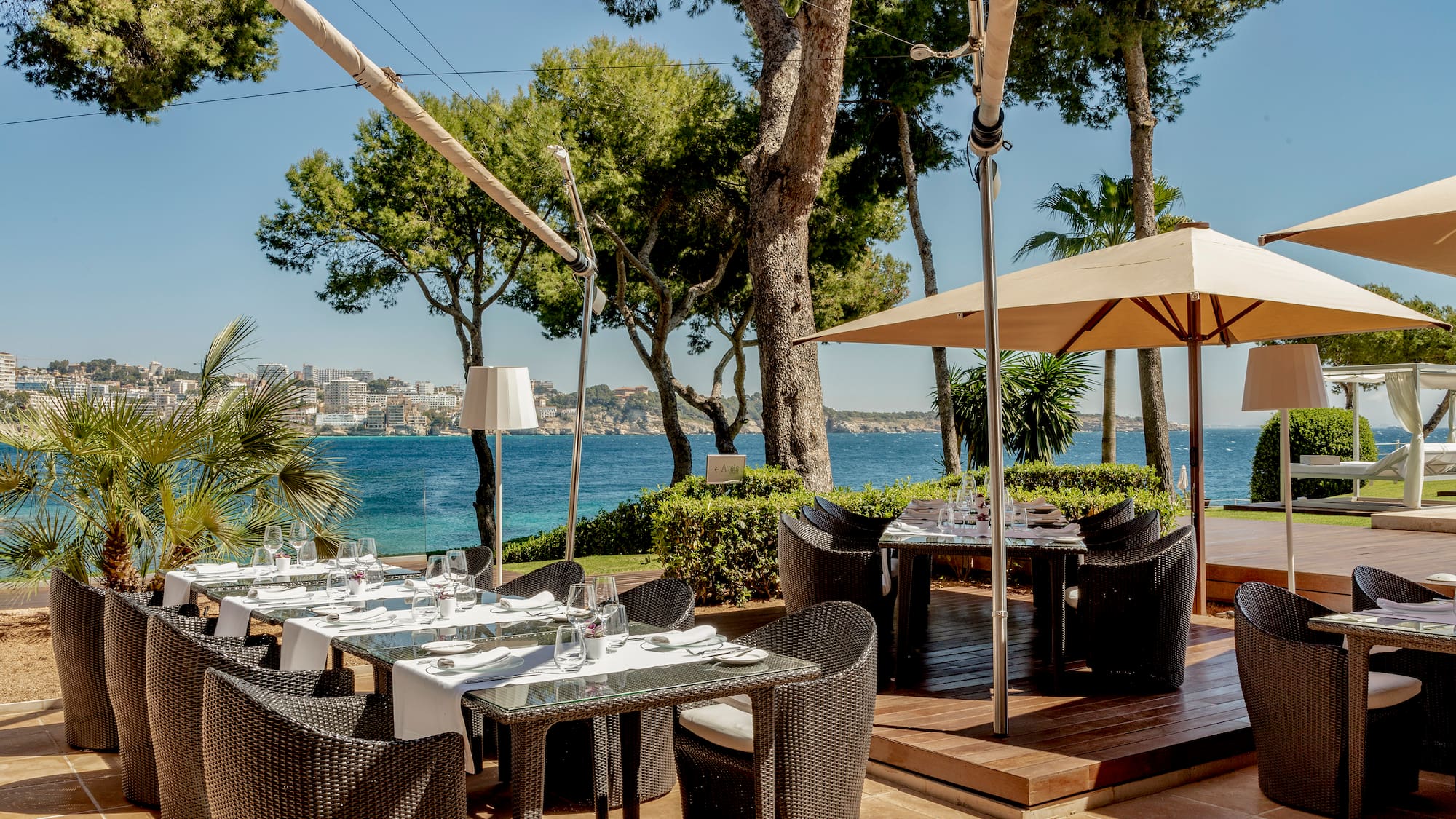 a table and chairs on a patio with a body of water in the background