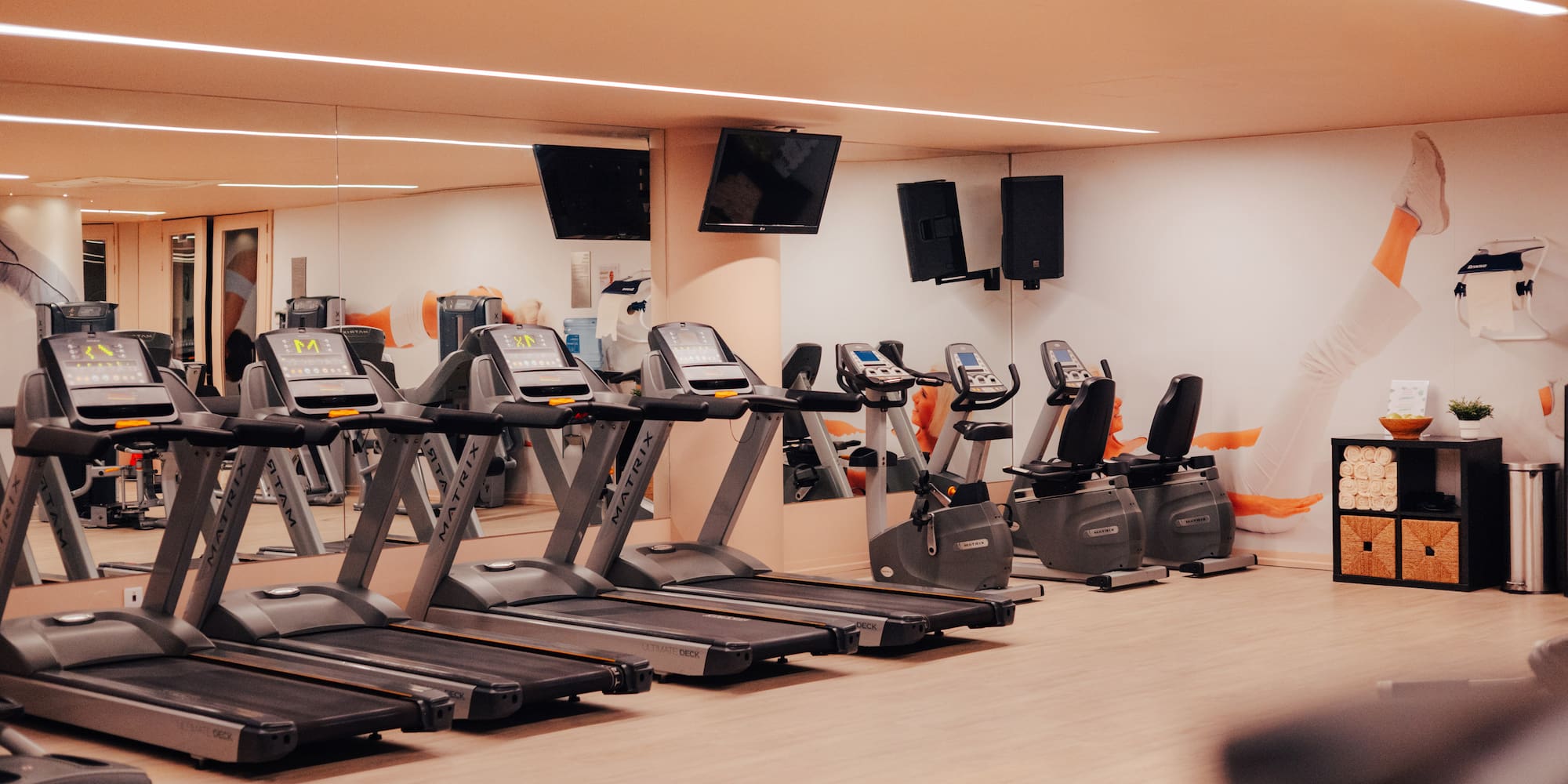 Modern gym with treadmills, exercise bikes, and wall mirrors.