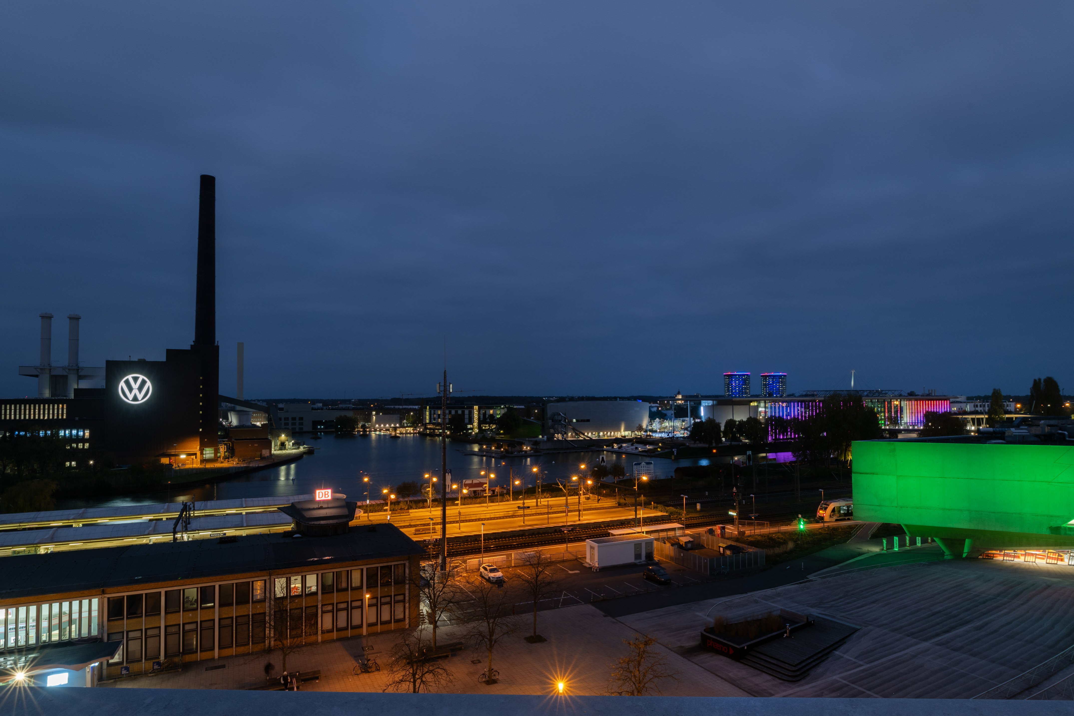 Illuminated VW factory, chimney, and city lights at night in Wolfsburg. - Sky Lounge & Bar The VIEW, Aperitivos - INNSiDE Wolfsburg, Wolfsburg