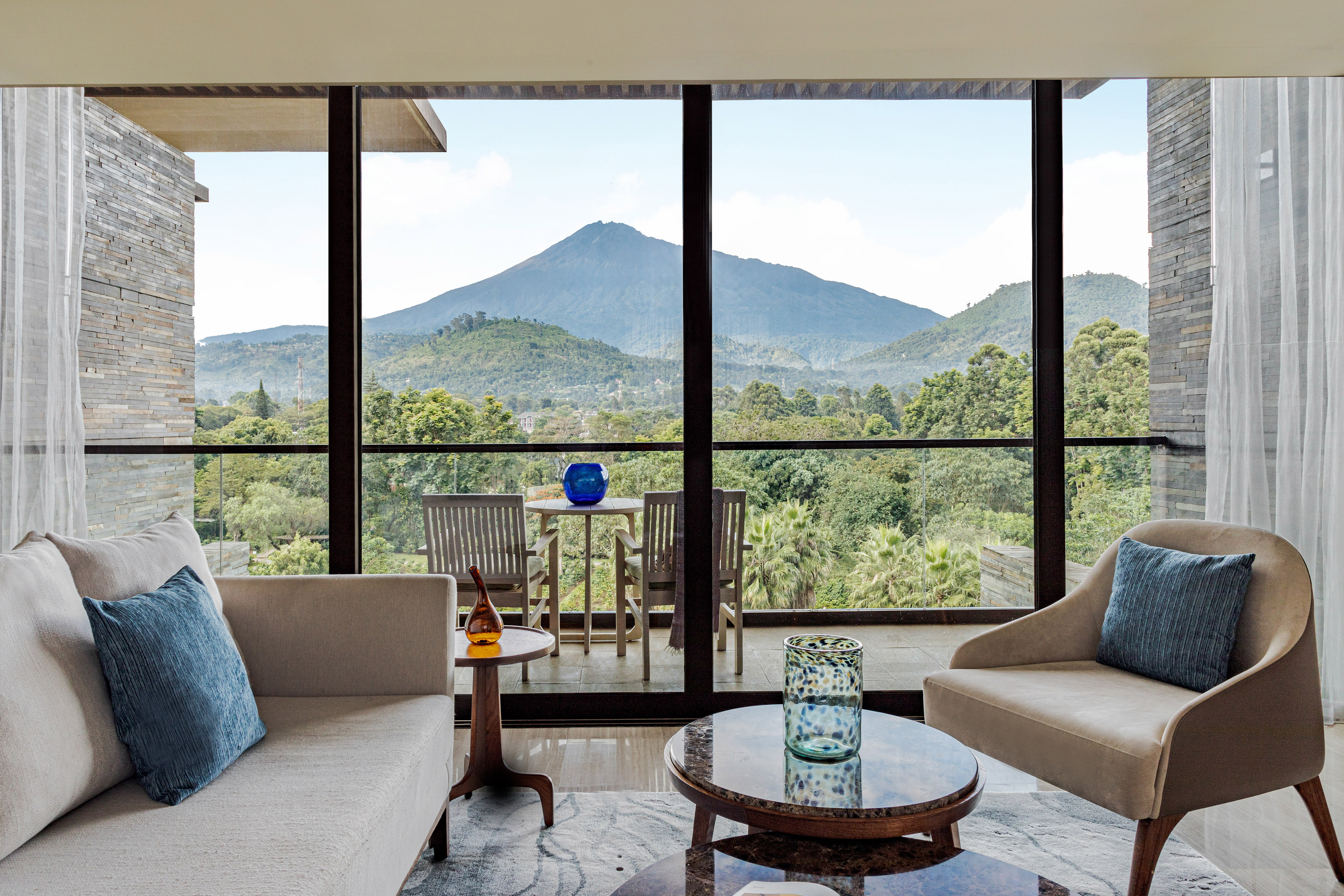 Modern living room with mountain and forest view from balcony.