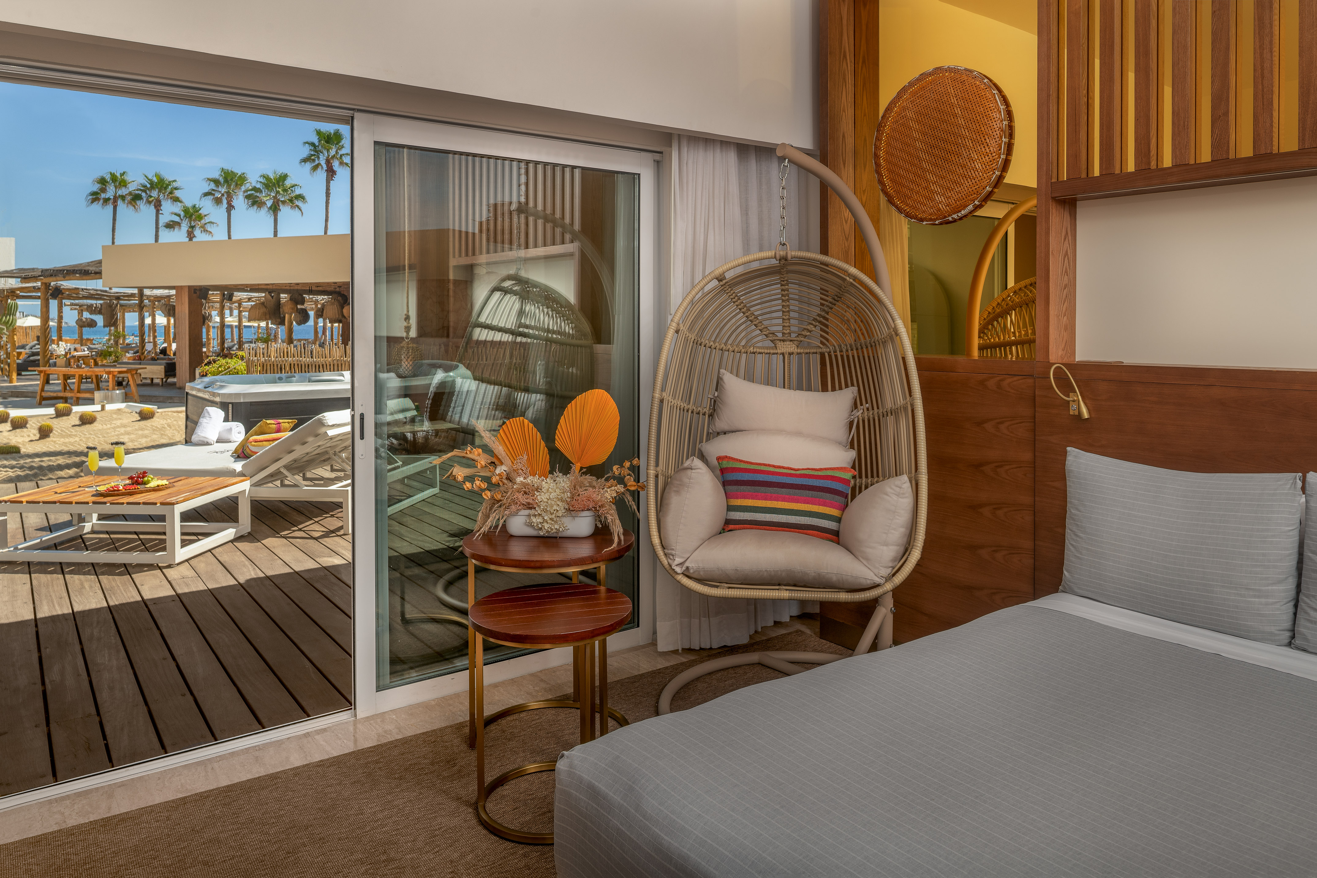 Resort suite: outdoor patio, hot tub, palm trees, and indoor hanging chair.