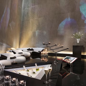 a room with a black floor and white couches and wine glasses