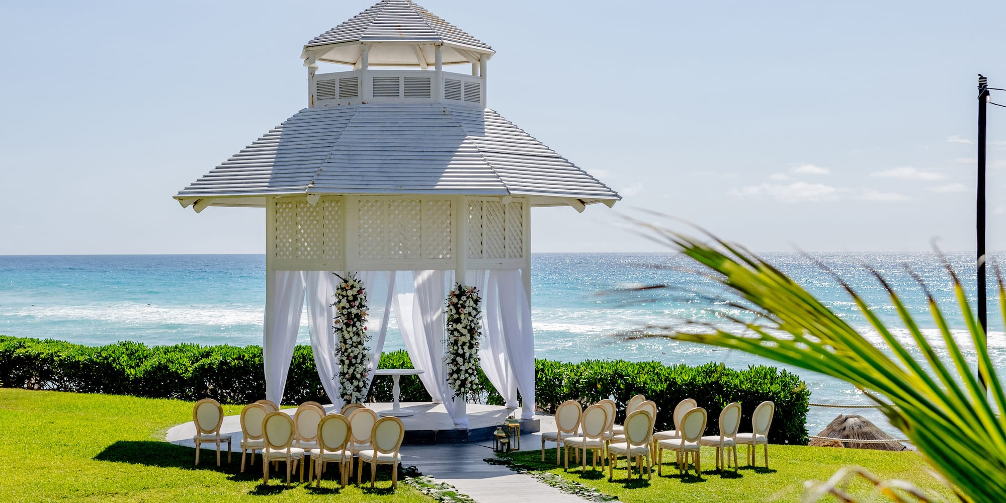 a gazebo with chairs and a walkway in front of the ocean