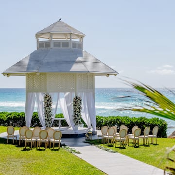 a gazebo with chairs and a walkway in front of the ocean