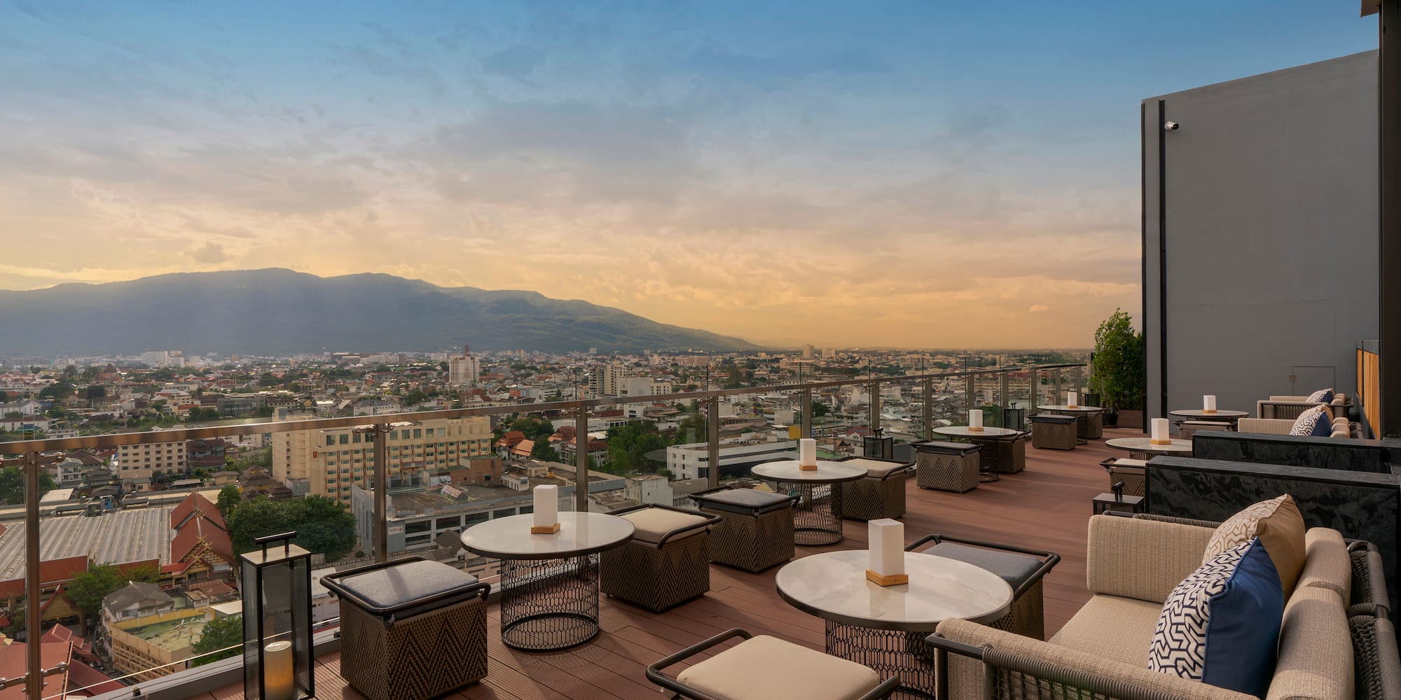 a rooftop patio with tables and chairs and a city view