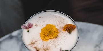 a glass with a drink and flowers on it