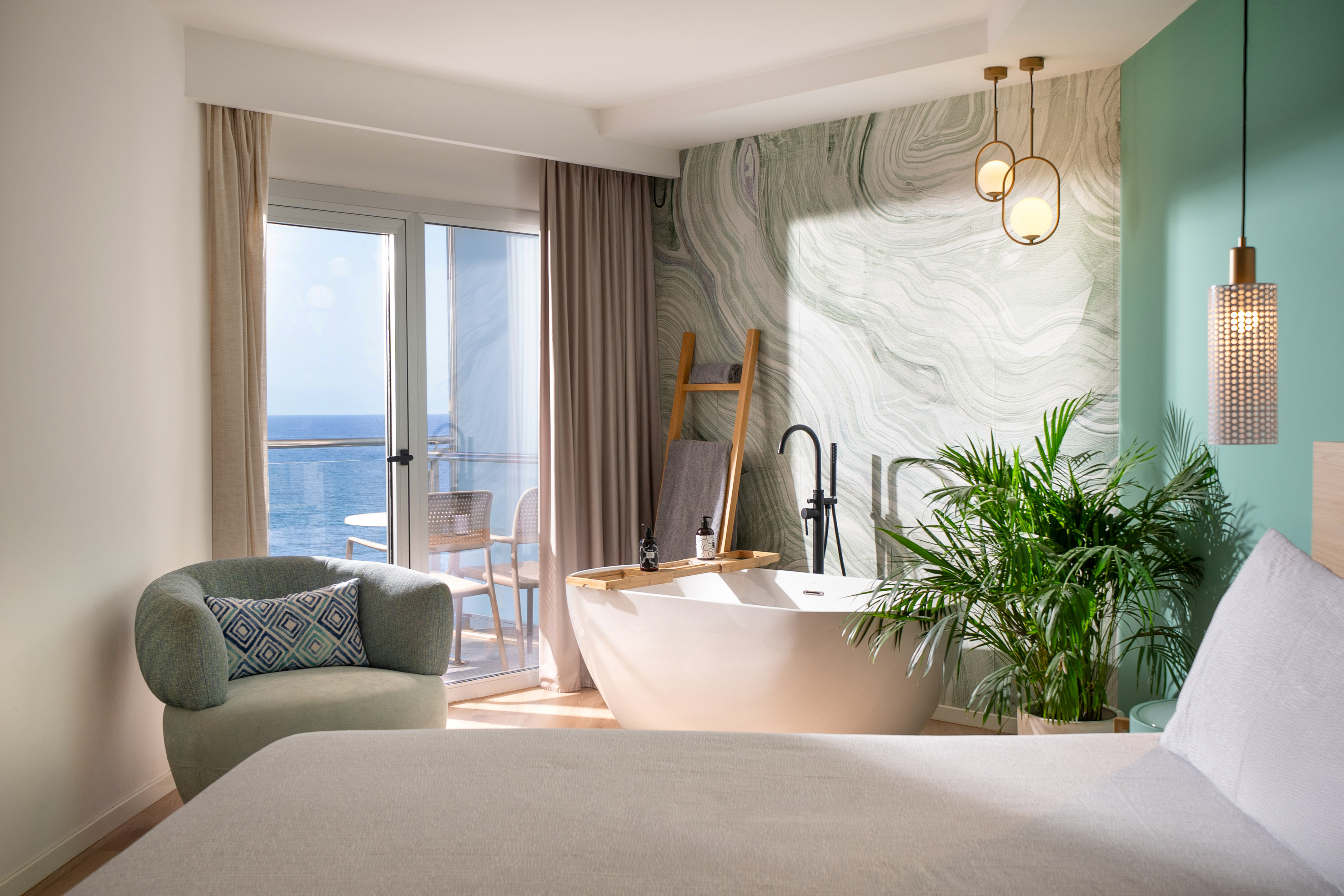 Modern hotel suite with in-room bathtub, sea view balcony, and stylish decor.